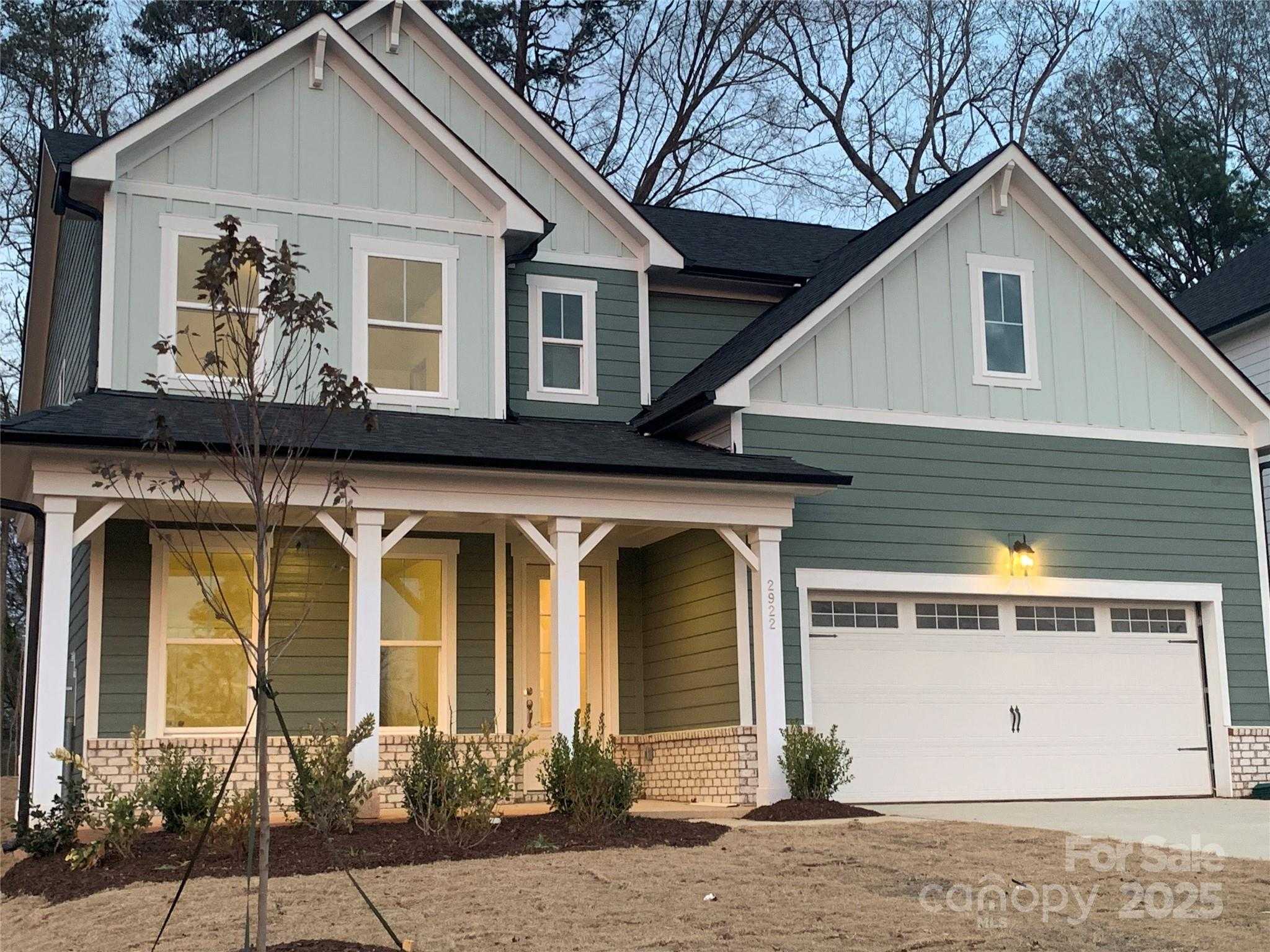 Two-story 5-bedroom home exterior with green siding, covered porch, 2-car garage in Enclave at Belmont, NC