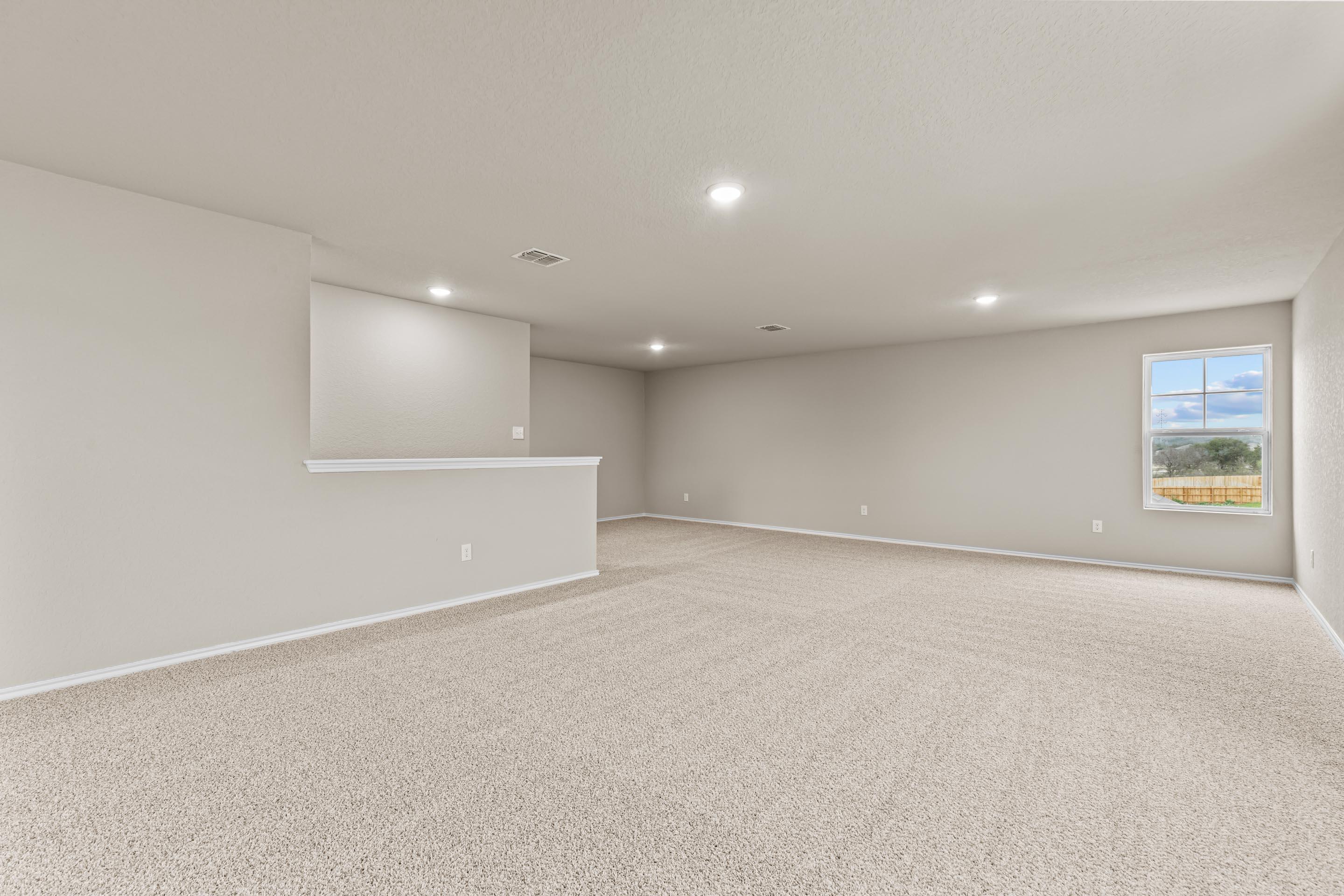 Spacious upstairs bonus room with built-in wet bar, neutral walls, plush carpet, and large window in Davidson Homes The Douglas F, San Antonio