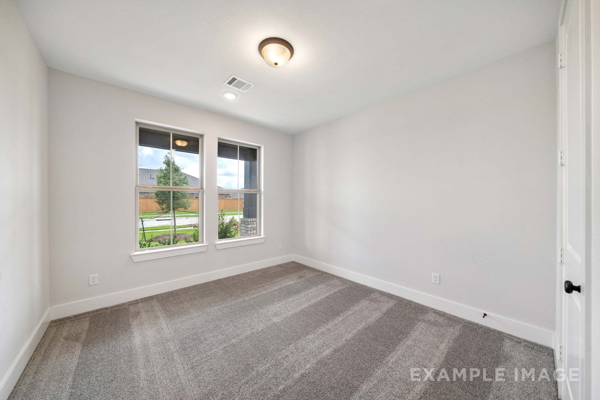 Spacious carpeted bedroom in The Victoria by Davidson Homes, featuring white walls, dual windows, and natural light in Texas City.