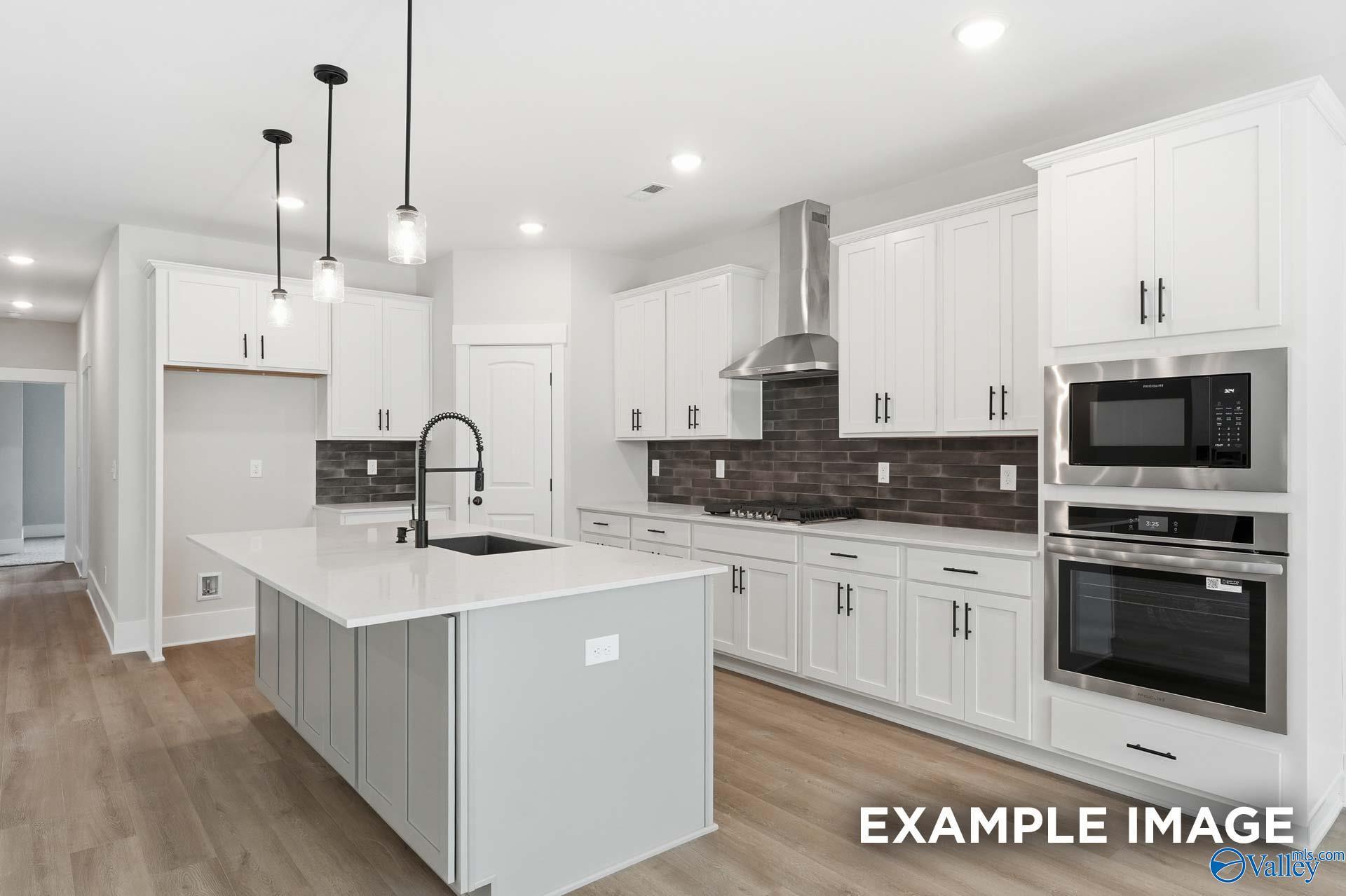 Modern kitchen with white cabinets, quartz island, and stainless appliances in The Rockford floor plan, Briercreek home.