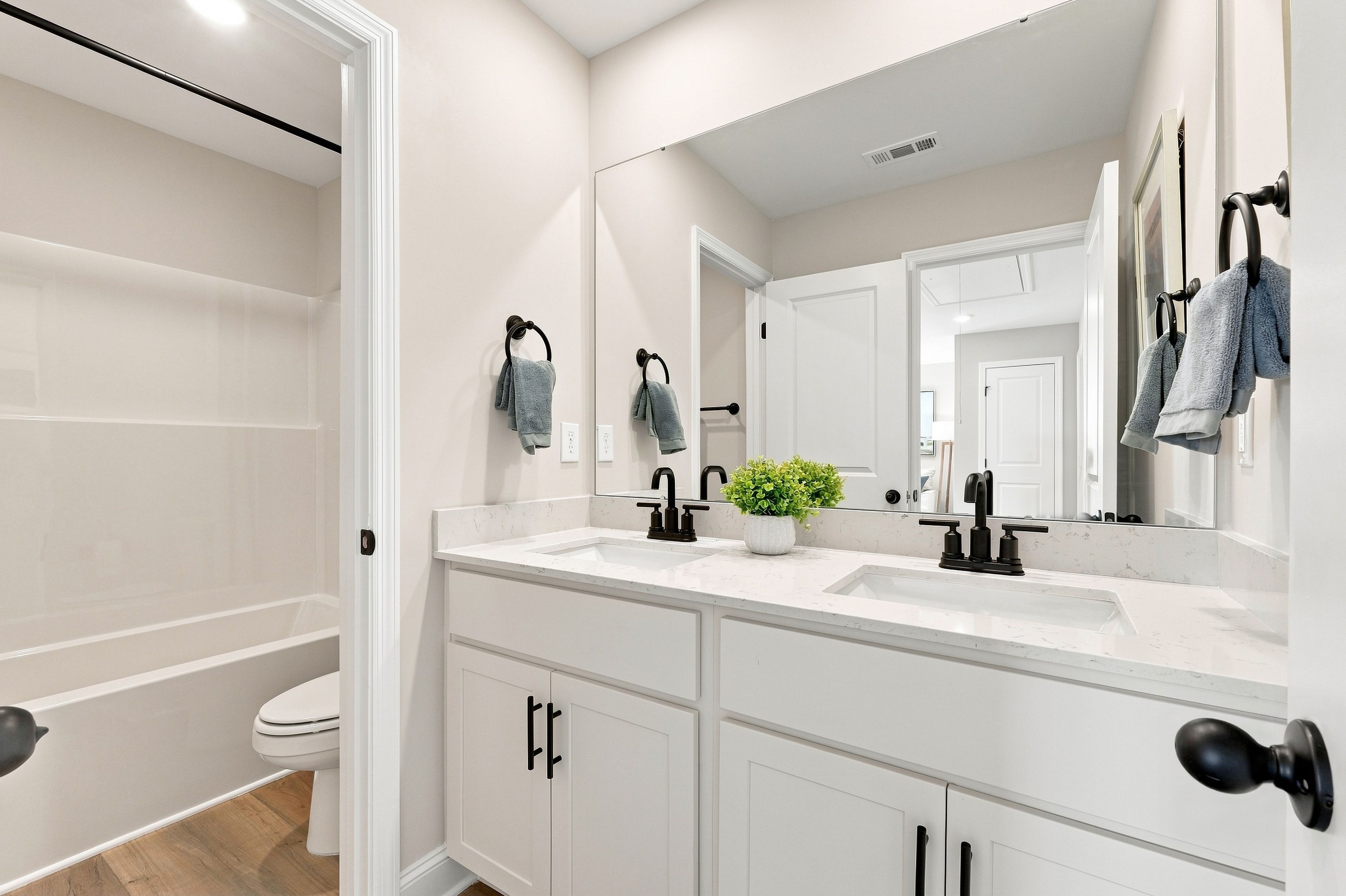 White double vanity bathroom with black fixtures and tile shower at Bailey Park by Davidson Homes in Fayetteville, Tennessee