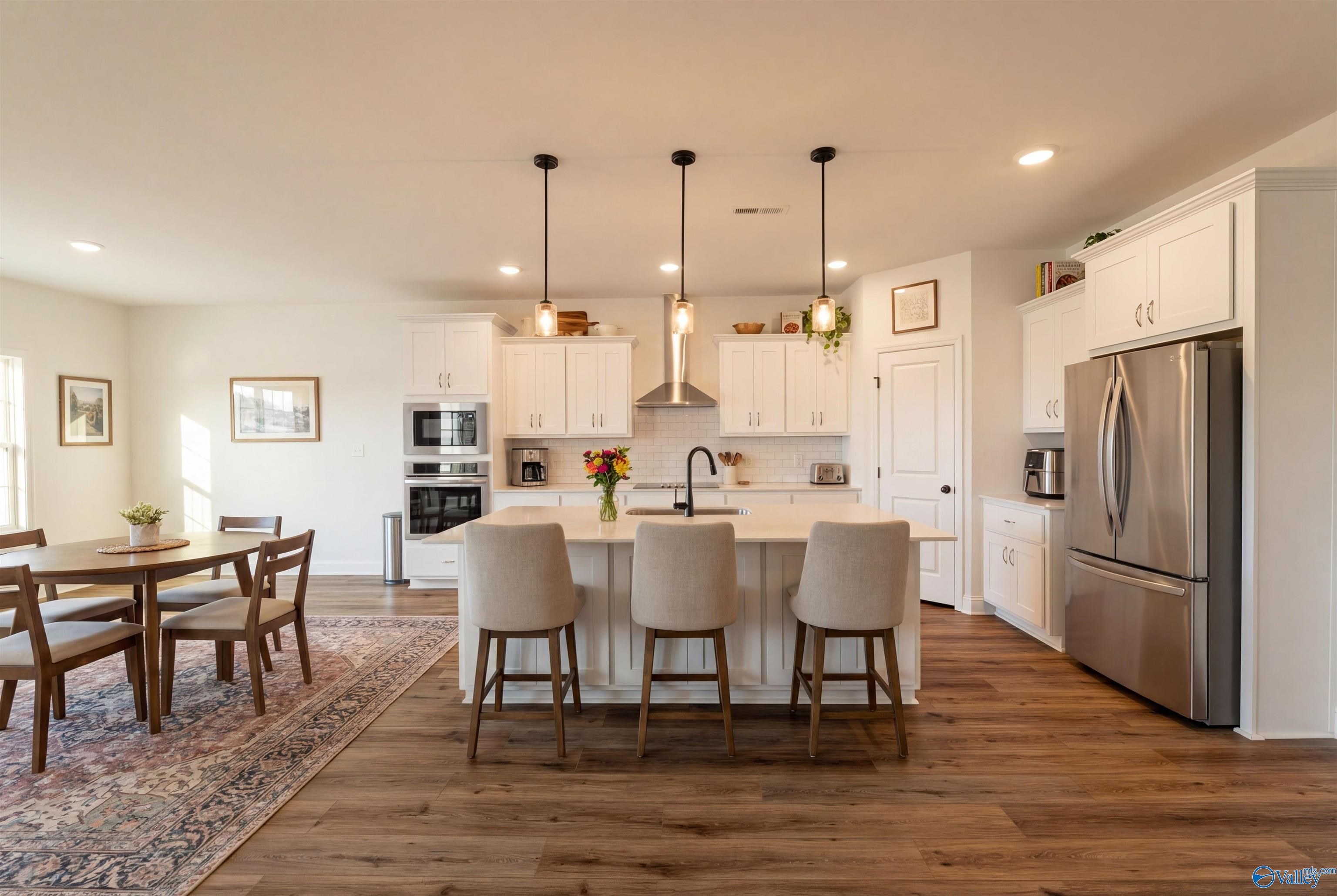 Modern open-concept kitchen with white cabinets, large island, stainless appliances in Davidson Homes Rockford B, Toney, Alabama