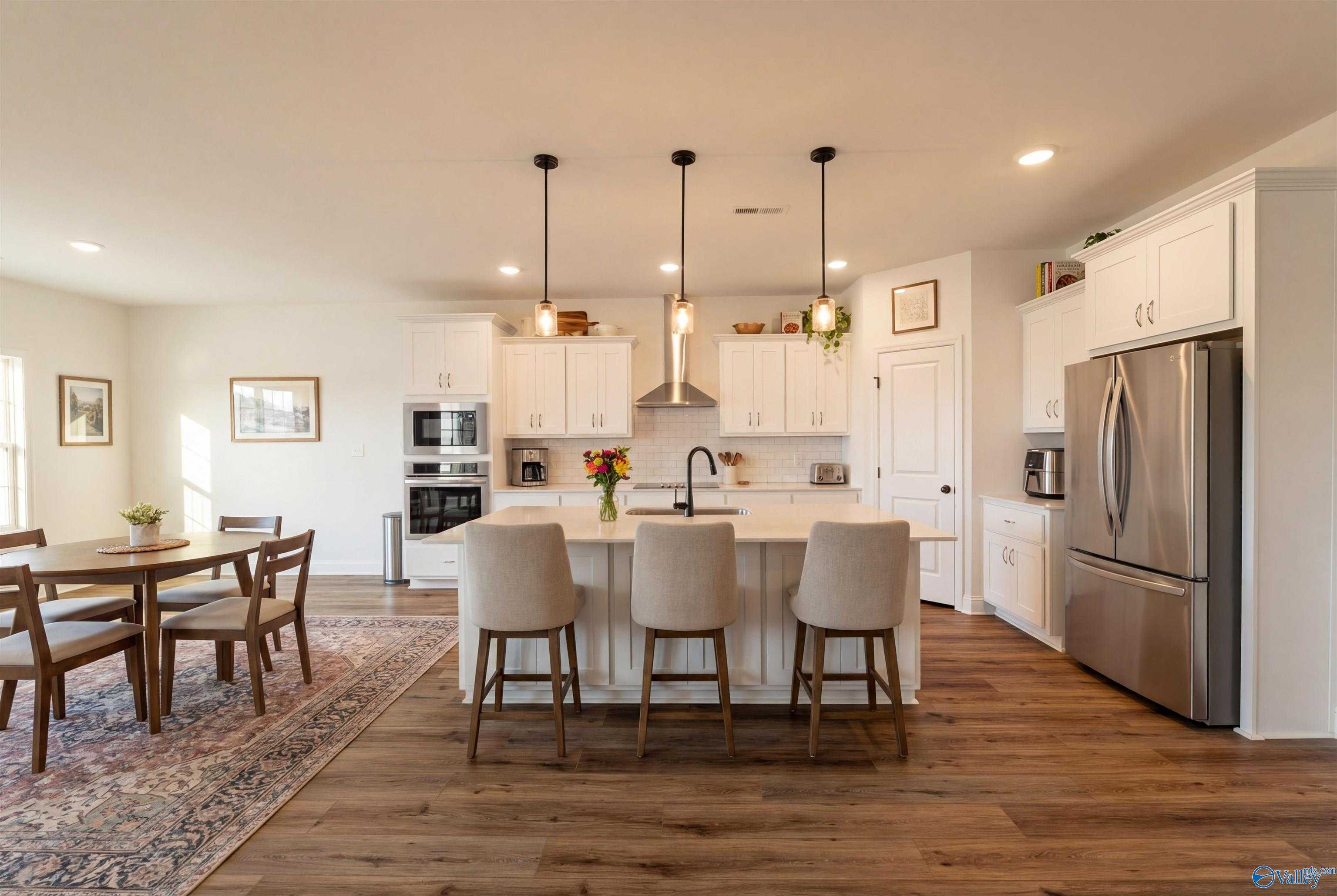 Modern open-concept kitchen with white cabinets, large island, stainless appliances in Davidson Homes Rockford B, Toney, Alabama