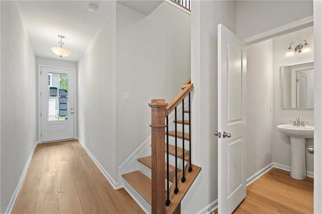 Bright entry hallway with oak staircase and adjacent powder room in Davidson Homes The Marion B, Kennesaw, Georgia