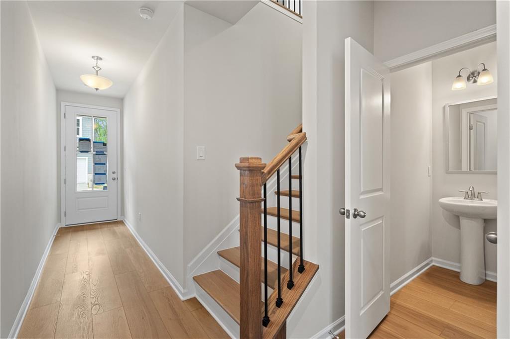 Entry hallway with hardwood floors, oak staircase and iron balusters, adjacent powder room with pedestal sink in Davidson Homes The Marion B, Kennesaw, GA