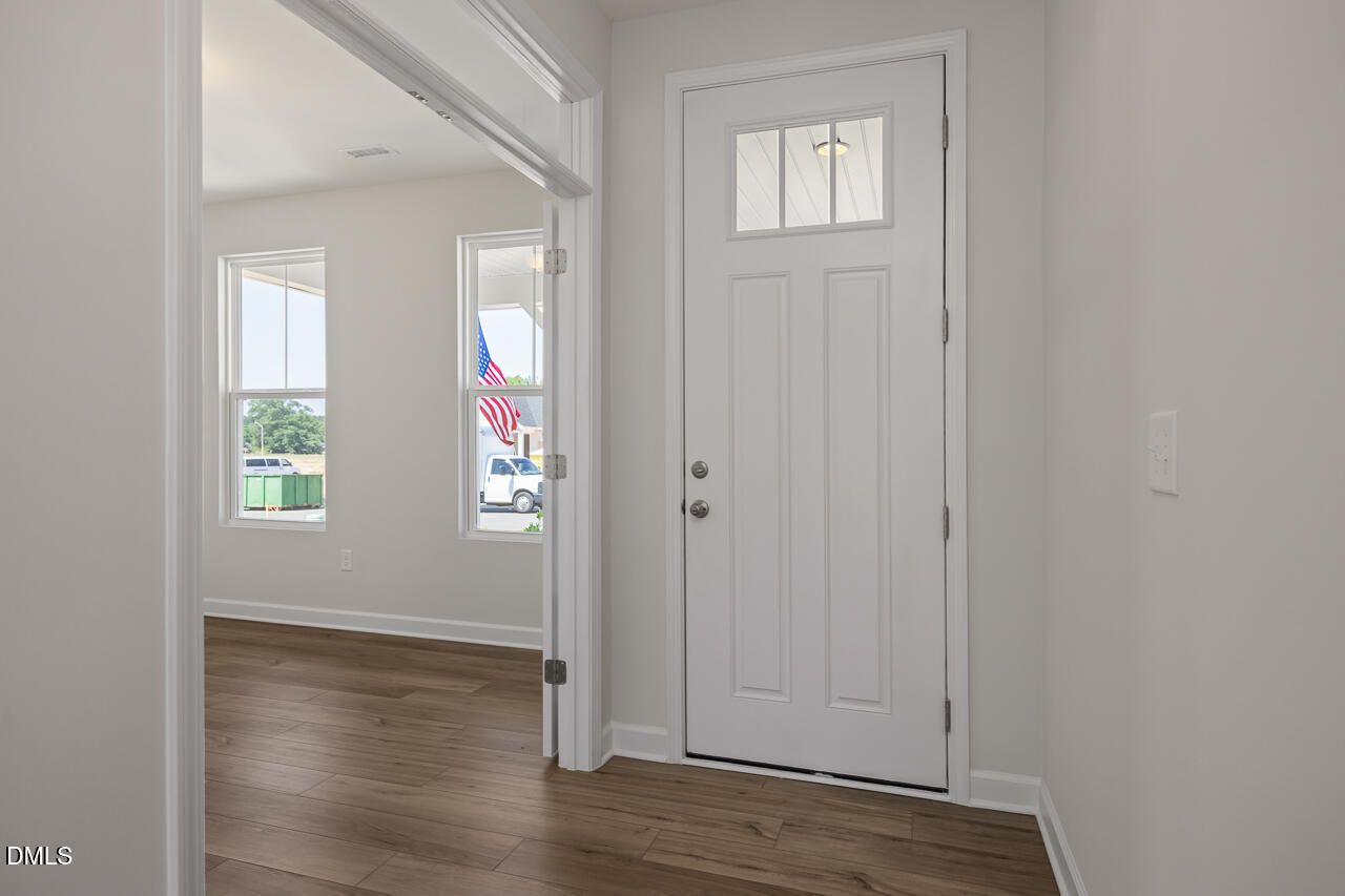 Bright foyer with white front door and wood-style flooring in The Chestnut B home, Retreat at North Main, Lillington, NC.