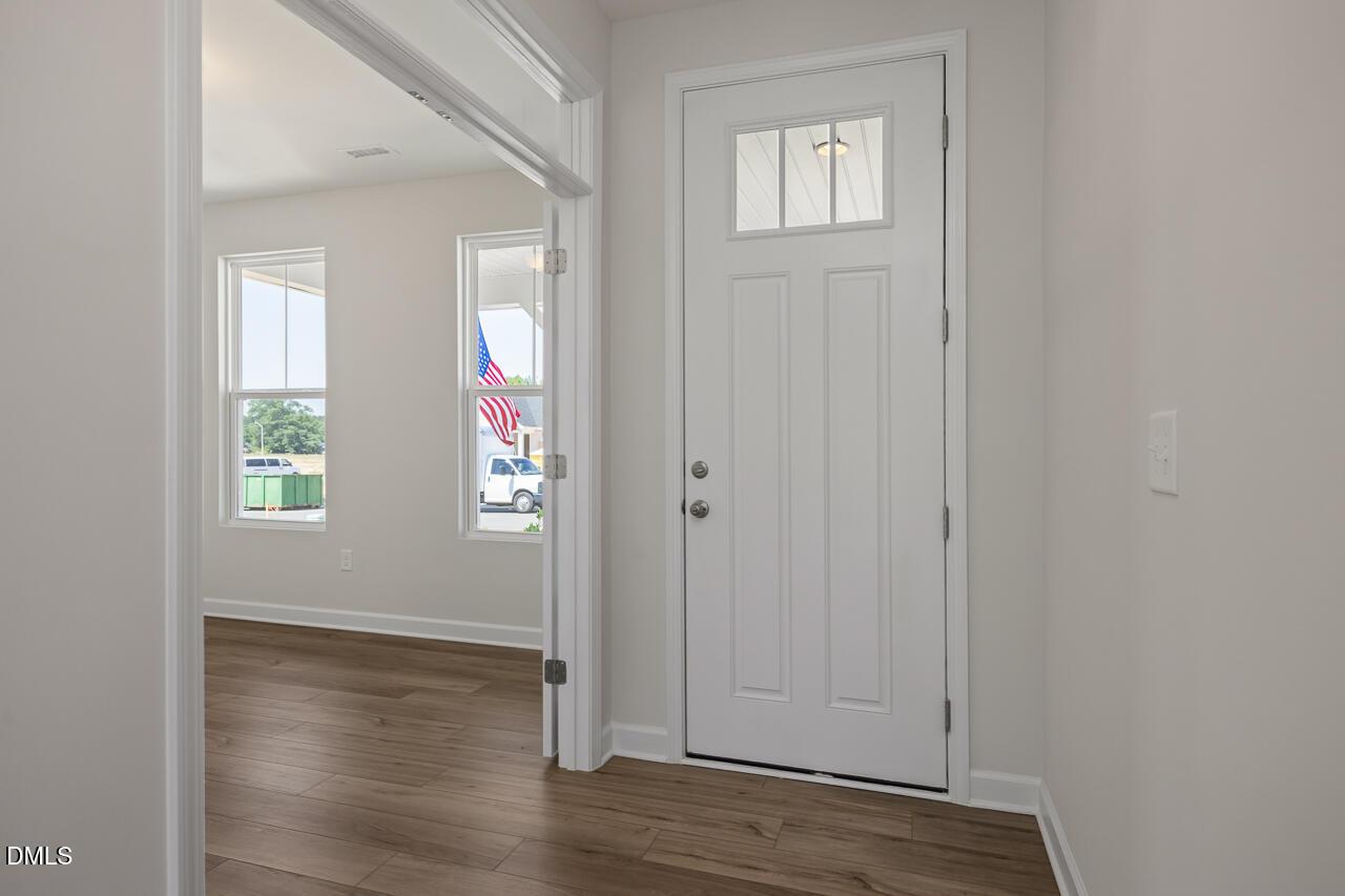 Bright entryway with white front door and wood-style flooring in The Chestnut B home, Retreat at North Main, Lillington.