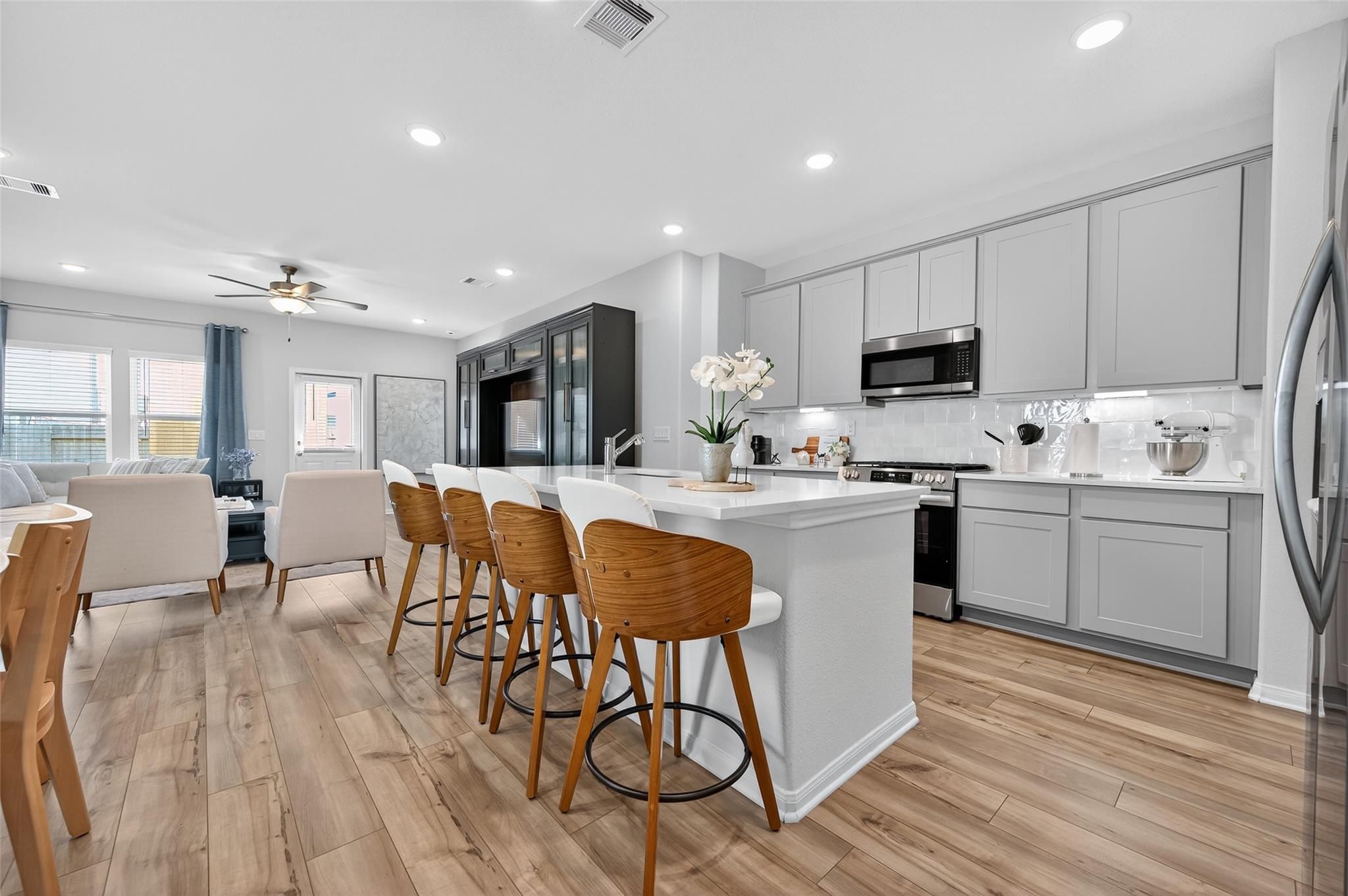 Spacious open-concept kitchen with white cabinets, quartz island, bar seating, stainless appliances in Davidson Homes The Brazos E, Magnolia, Texas