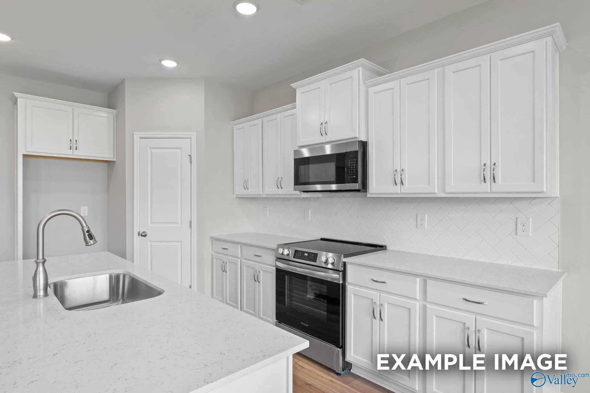 Bright modern kitchen with white shaker cabinets, stainless steel appliances, quartz island in Davidson Homes The Montgomery B, Hartselle AL