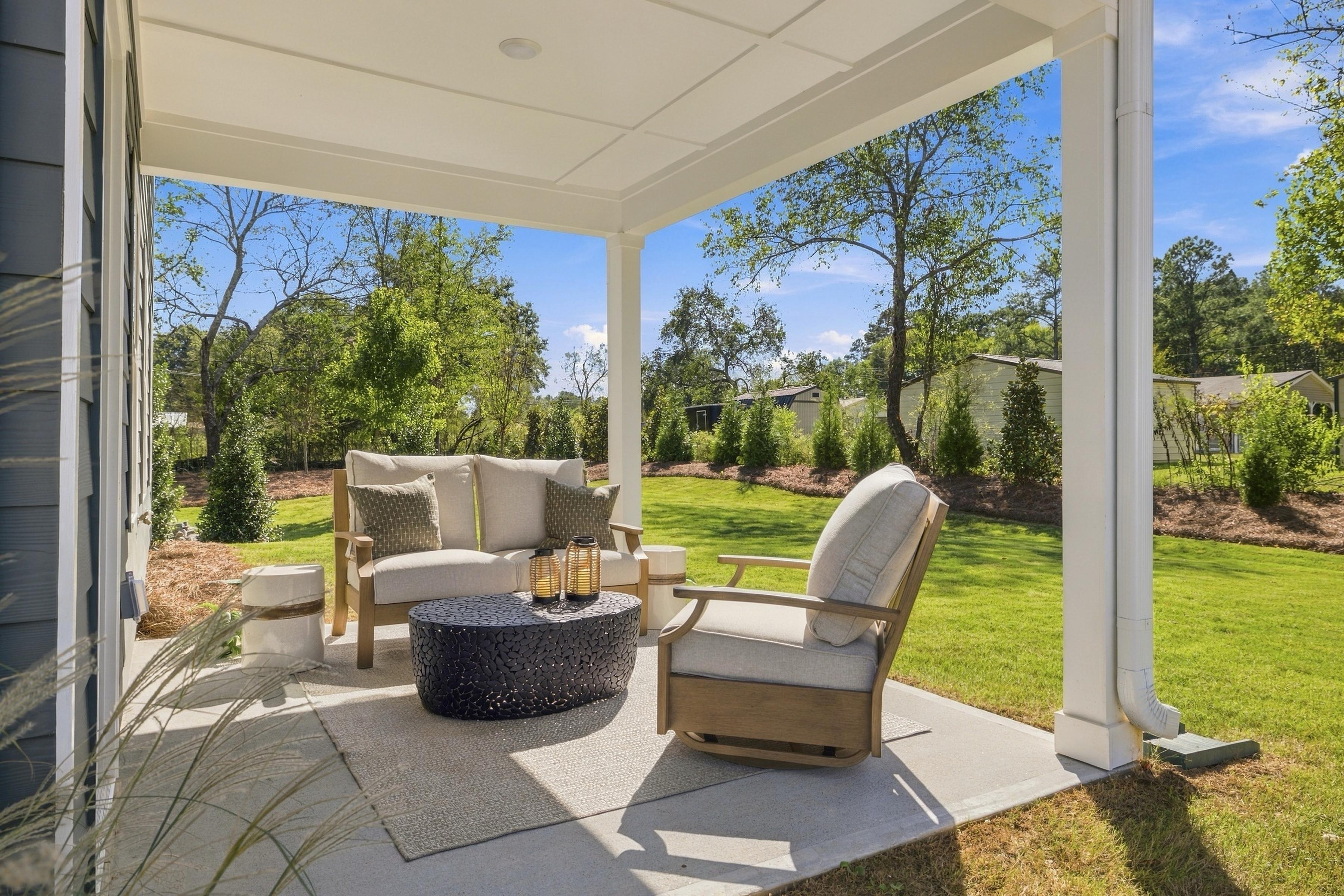 Covered back porch with outdoor seating overlooking backyard lawn at Greene Farm by Davidson Homes in Cartersville, Georgia