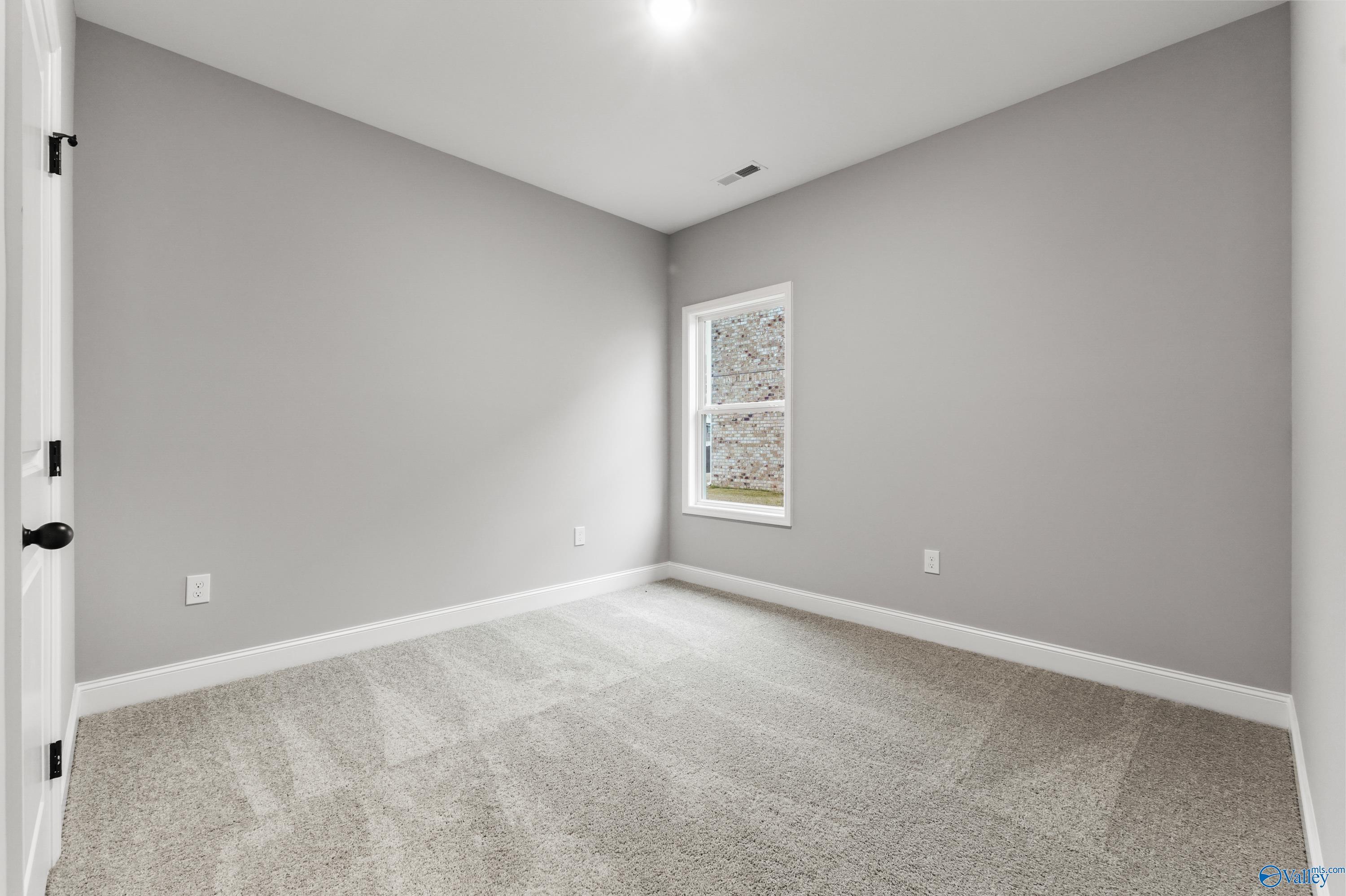 Bright secondary bedroom with light gray walls, neutral carpet, and large window in Davidson Homes The Asheville C, Meridianville, Alabama