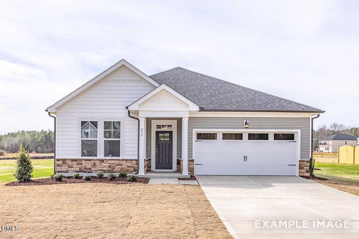 Modern white 1-story home with gabled roof, 2-car garage, front porch, and brick accents in Wellers Knoll, Lillington, NC - Davidson Homes Daphne C