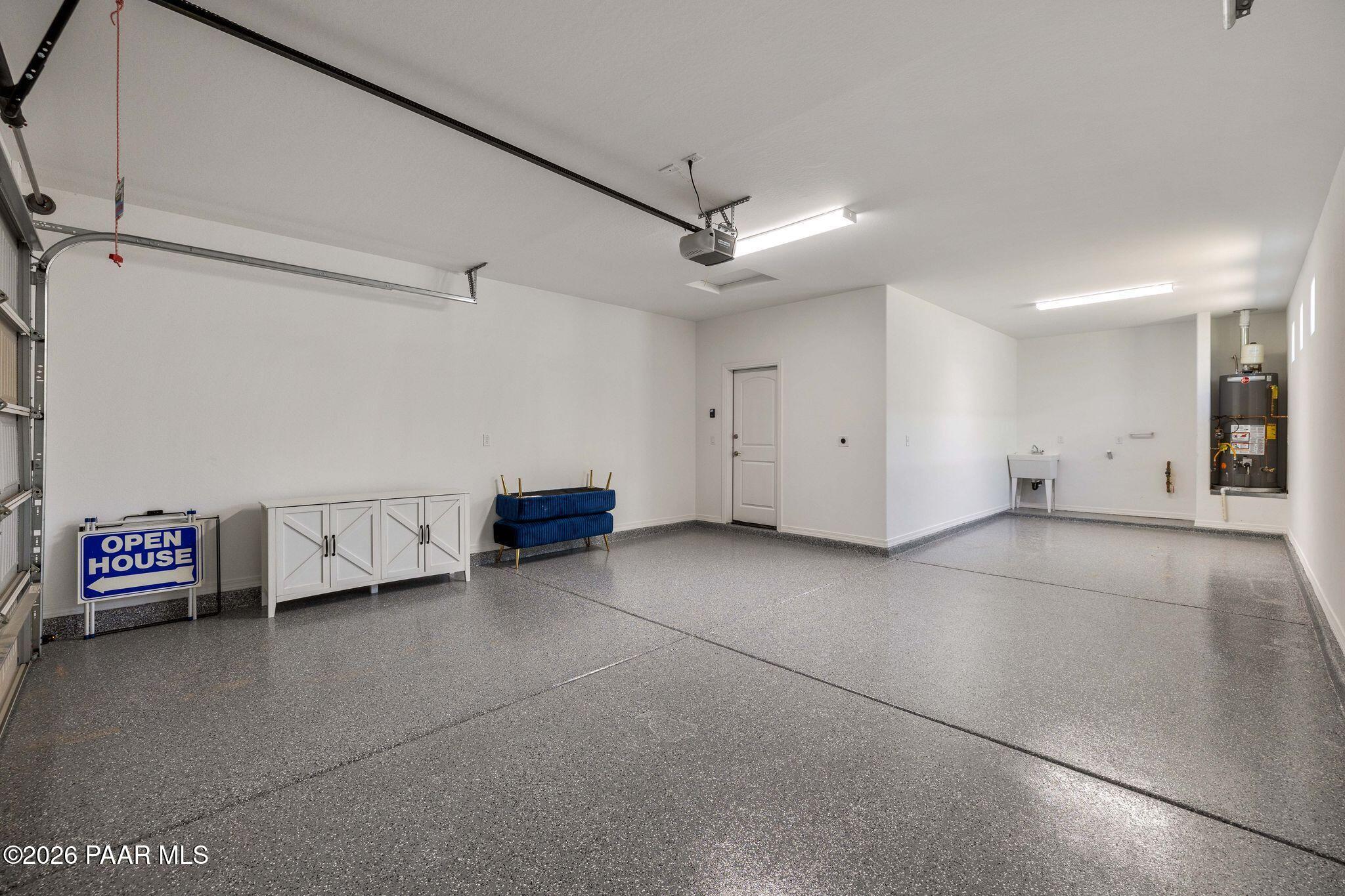 Spacious 3-car garage with epoxy flooring, storage cabinets and open house sign in Davidson Homes The Frontier A, Prescott Valley, Arizona