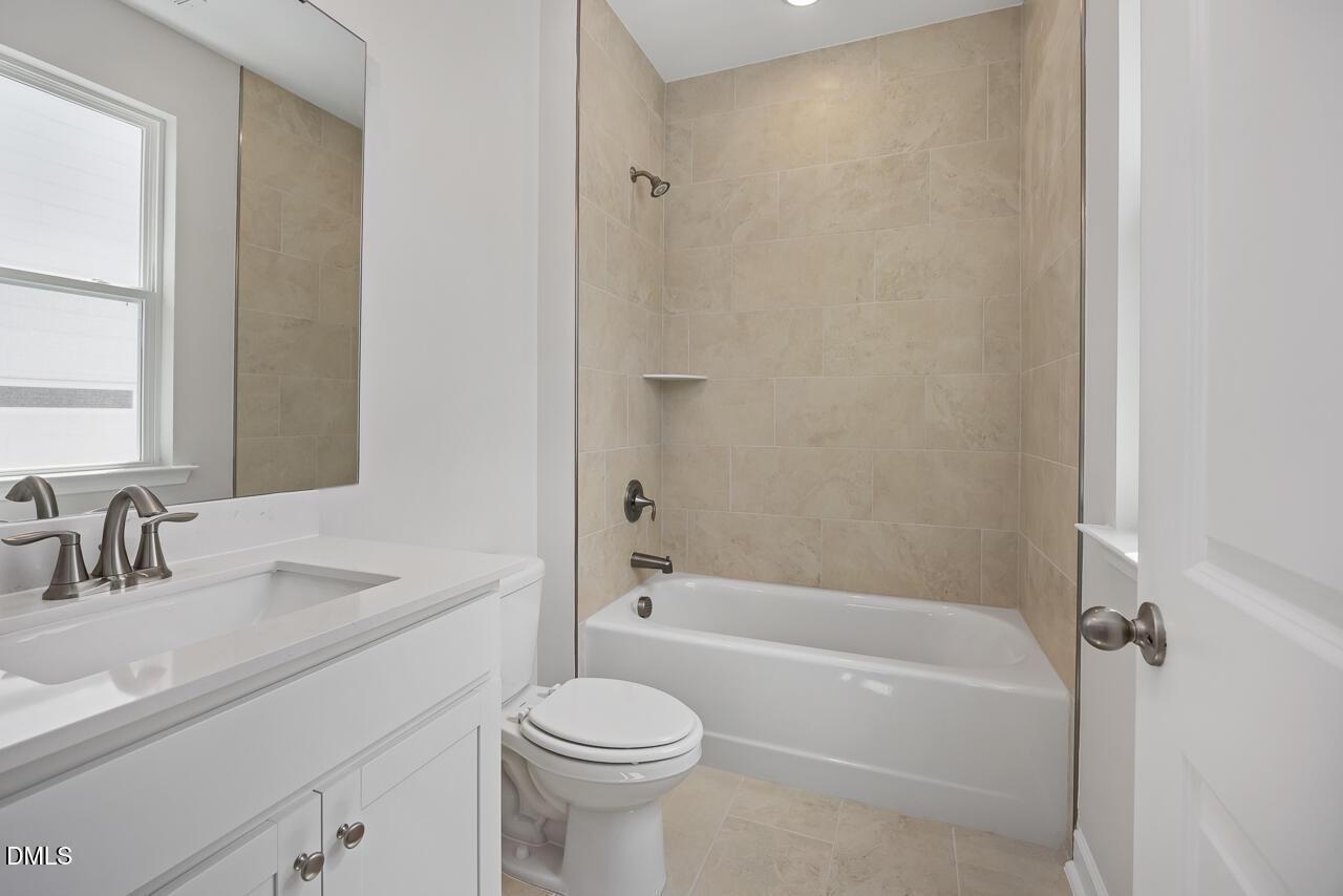 Modern bathroom with tub-shower combo and white vanity in The Ashport L floor plan at Sage on North Main, Wake Forest, NC.