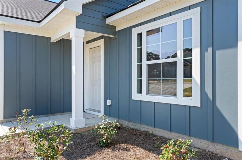 Blue-sided 3-bedroom home exterior with white-trimmed front door, columned porch, and large window in Summer Vineyard, Phenix City, Alabama