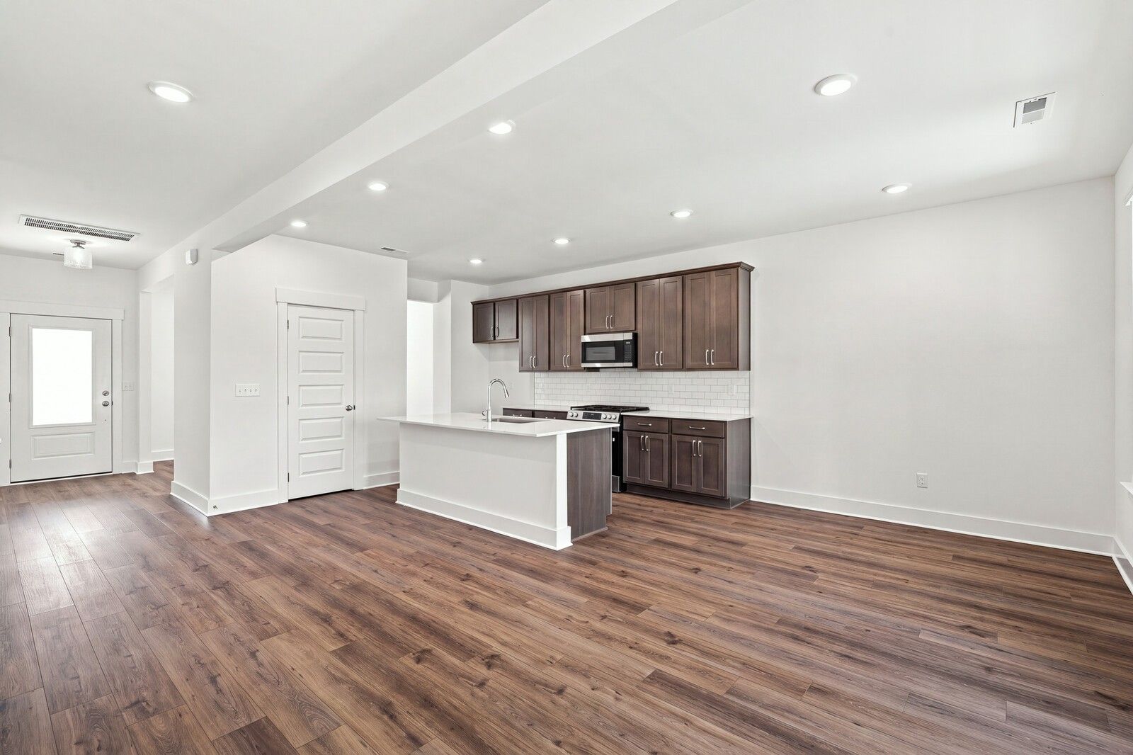 Open-concept kitchen with white island, dark cabinets, and luxury vinyl plank flooring in Davidson Homes Willow C, Gallatin TN