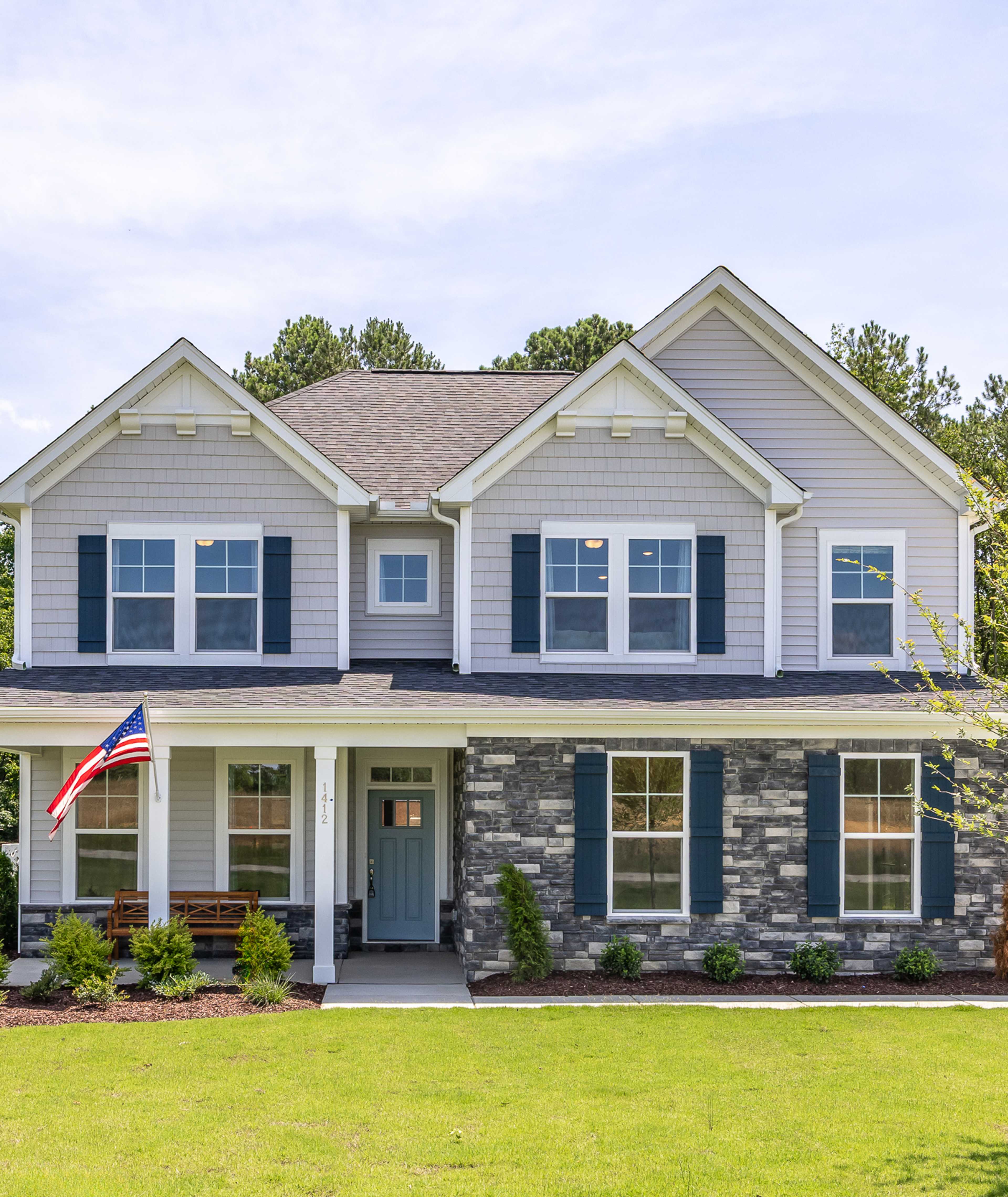 Open-concept living room at Retreat at North Main in Lillington NC with gray sectional sofa, hardwood floors, arched mirror, and modern kitchen