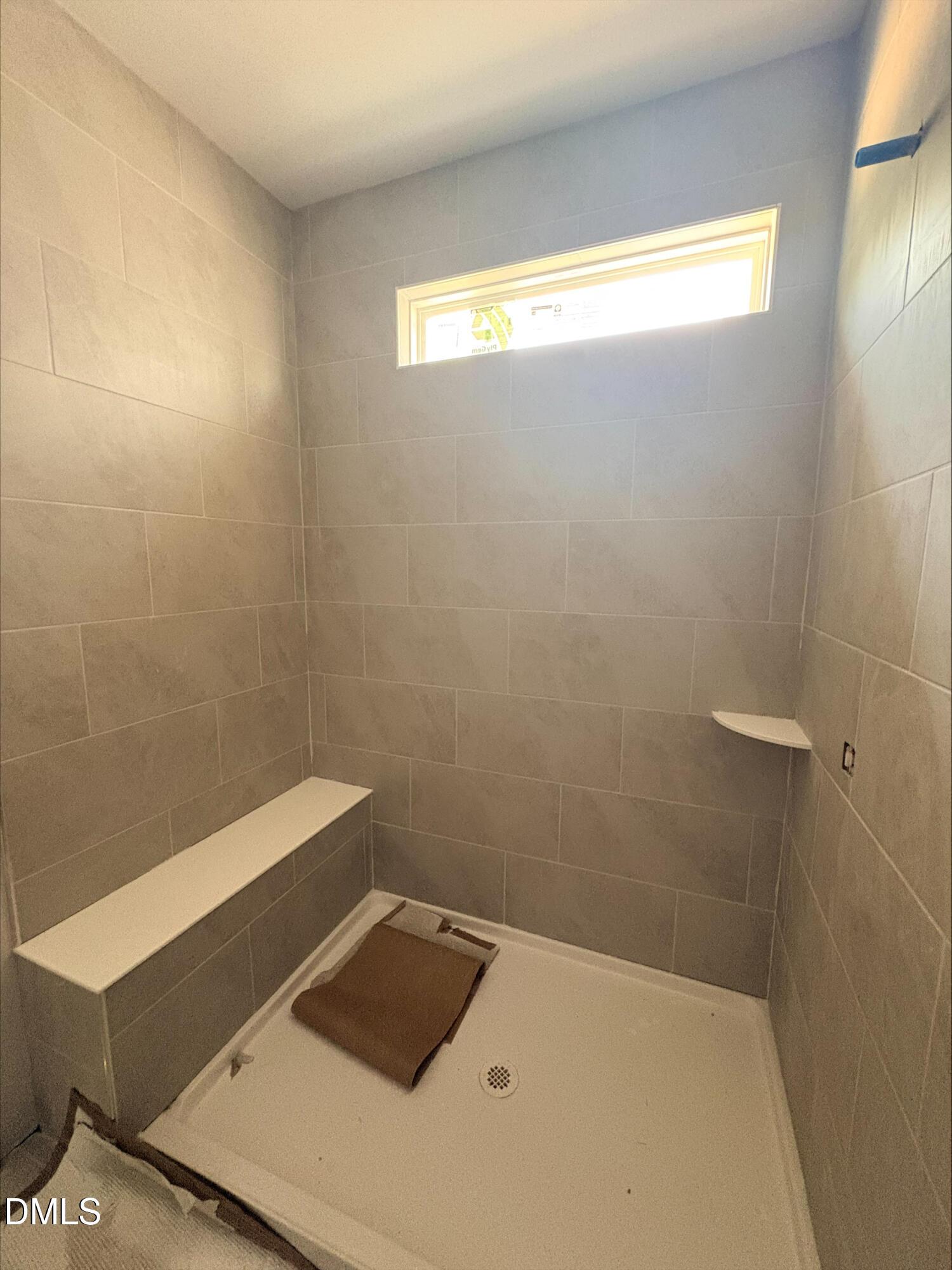 Tiled walk-in shower with built-in bench in The Daphne D floor plan at Woodland Crossing in Zebulon, North Carolina.