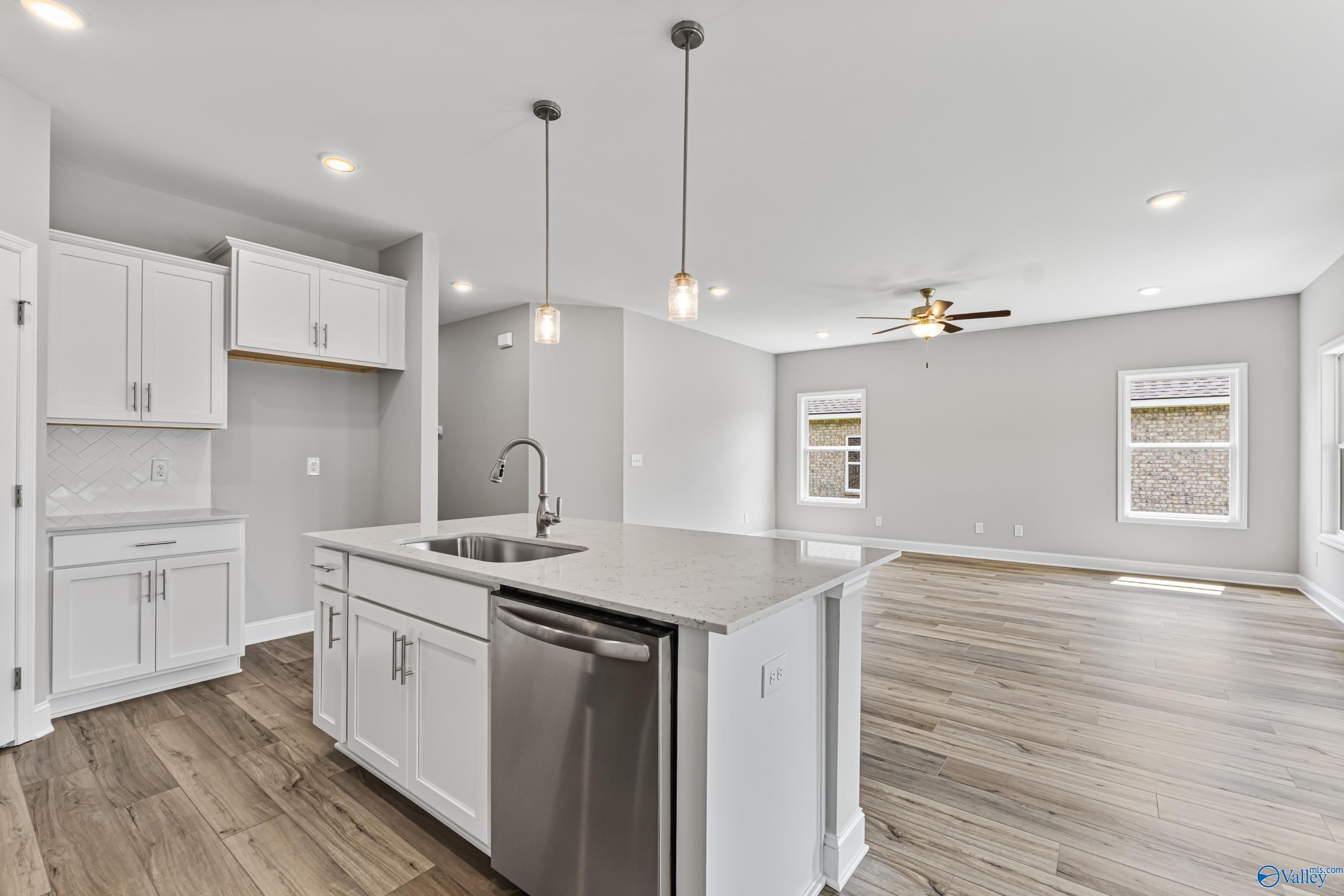 Modern white kitchen with quartz island, stainless dishwasher, hardwood floors in Davidson Homes The Franklin C, Huntsville AL