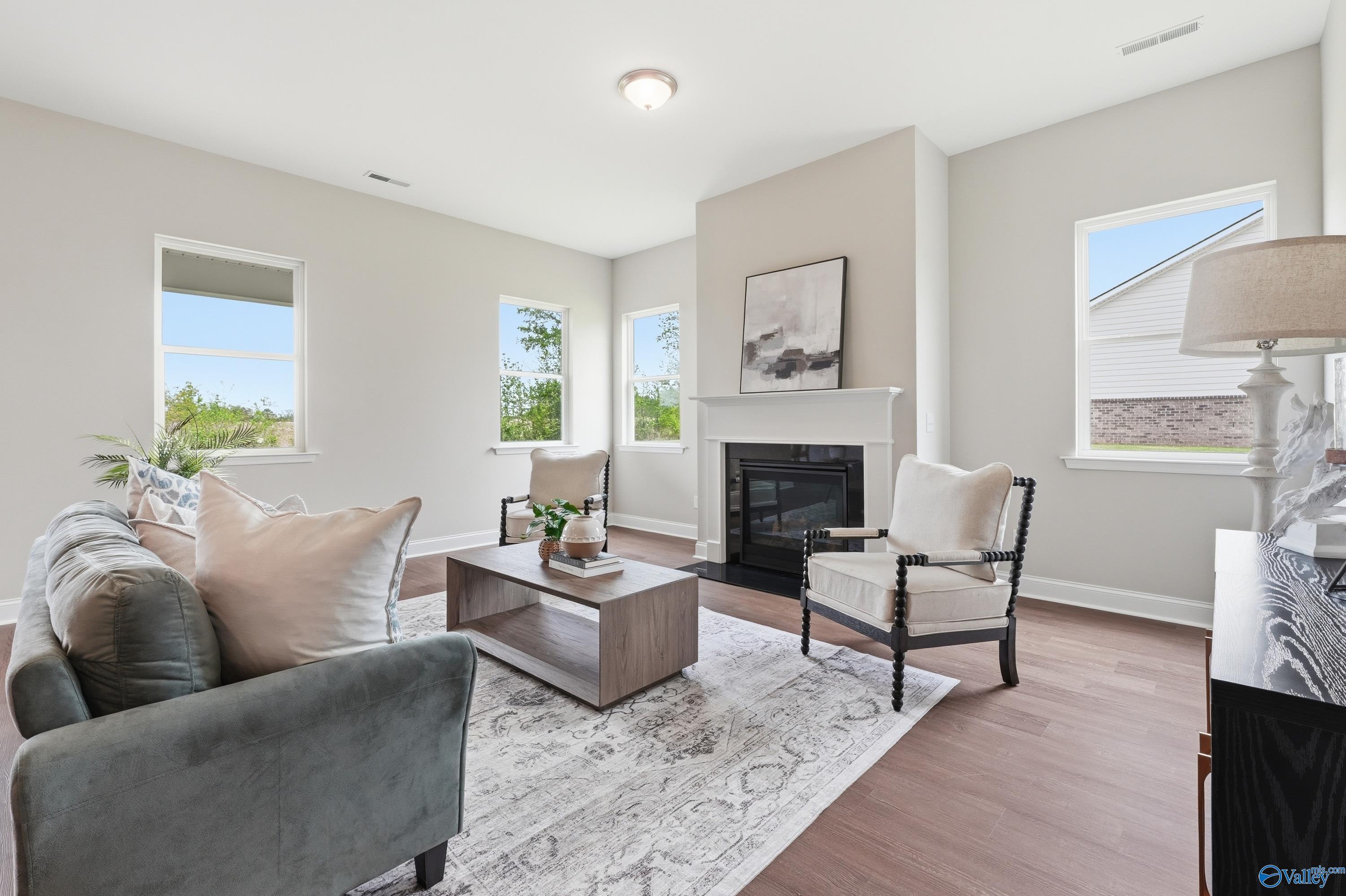 Cozy living room with gray sectional sofa, gas fireplace, and large windows in Davidson Homes The Arcadia B, Huntsville, Alabama