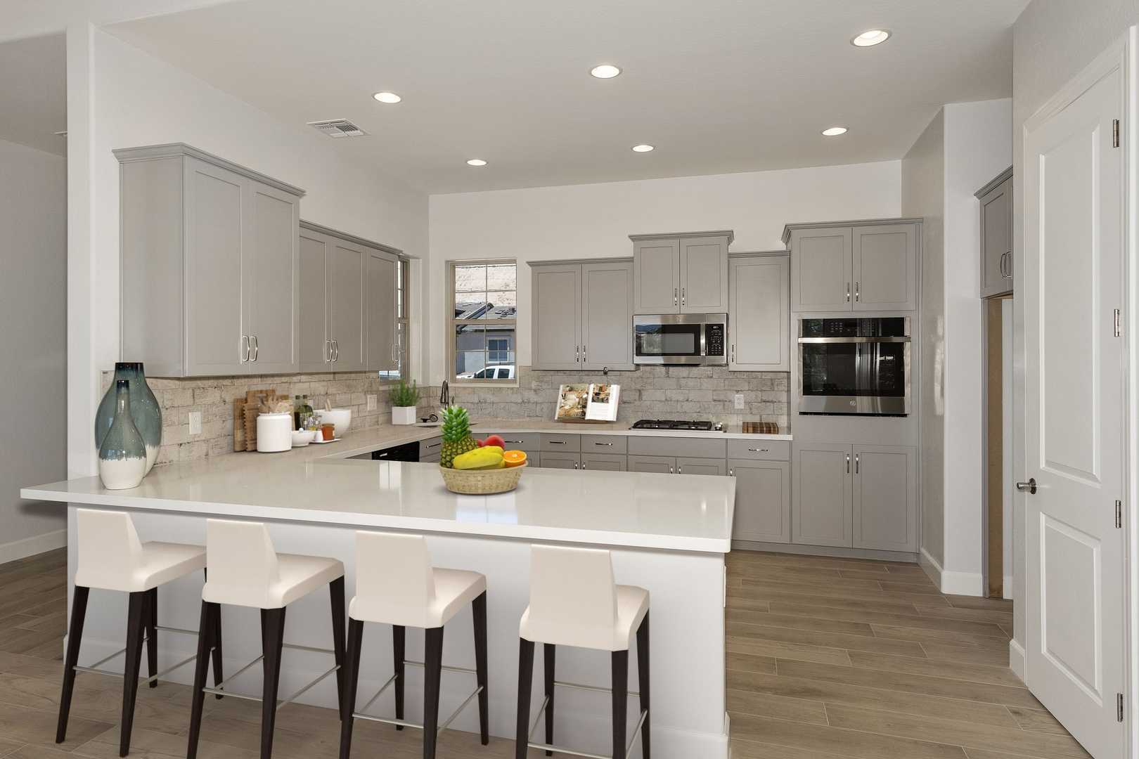 Gourmet kitchen in The Daybreak Davidson Homes design featuring white quartz island, gray cabinets, bar seating, and open layout