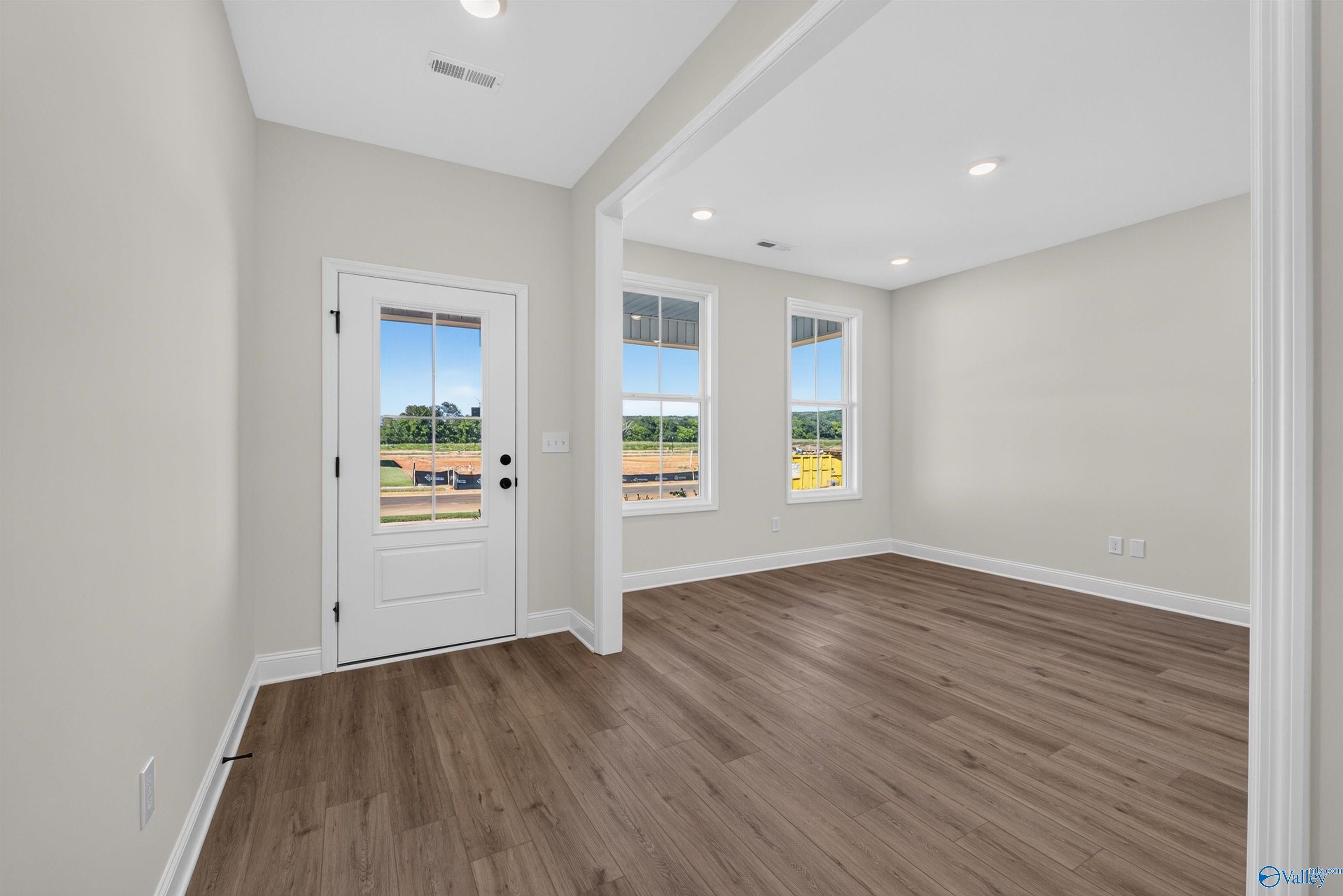 Bright entryway with glass-panel white front door and luxury vinyl plank flooring in Davidson Homes Ashport L, New Market, AL