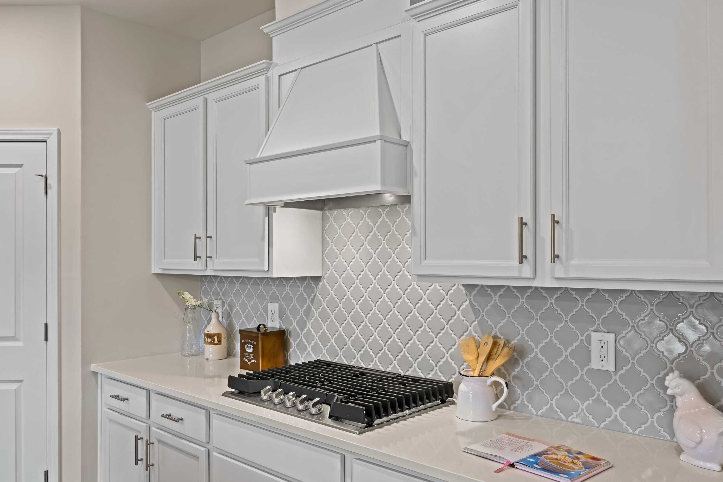 Modern kitchen at Gregory Village in Lillington NC featuring white shaker cabinets, gas range, and herringbone tile backsplash
