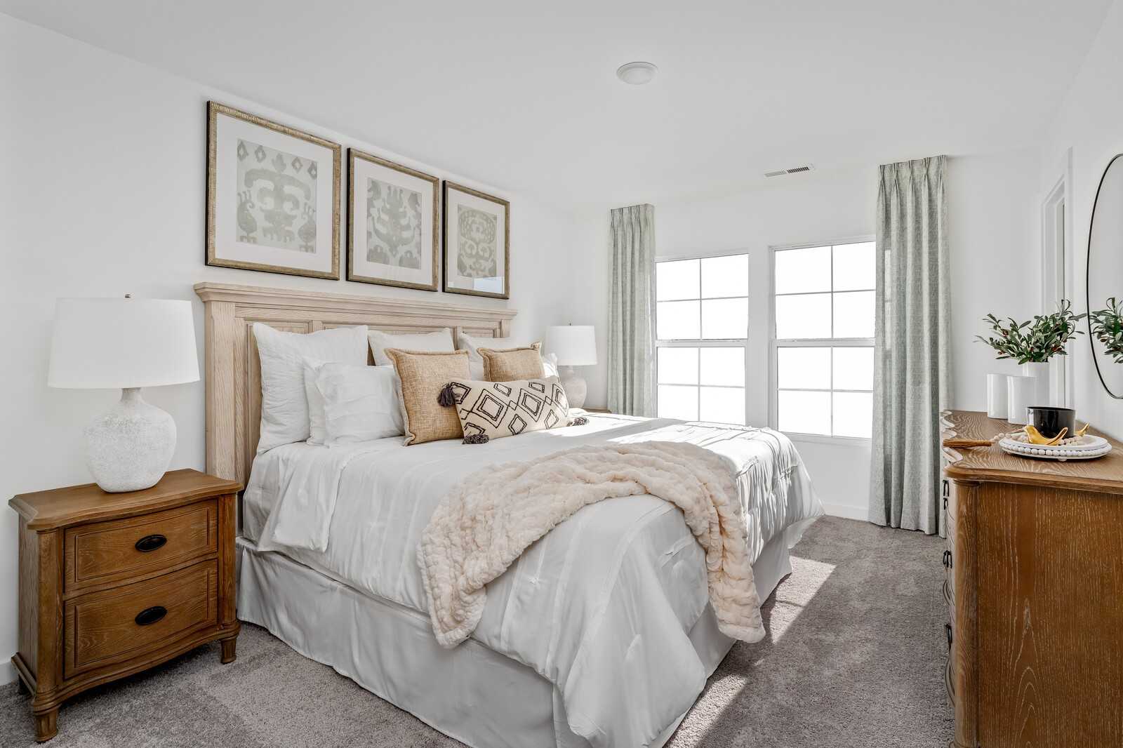 Serene secondary bedroom with plush white bedding, wooden nightstands, and large windows in Davidson Homes The Cumberland A, Gallatin, Tennessee