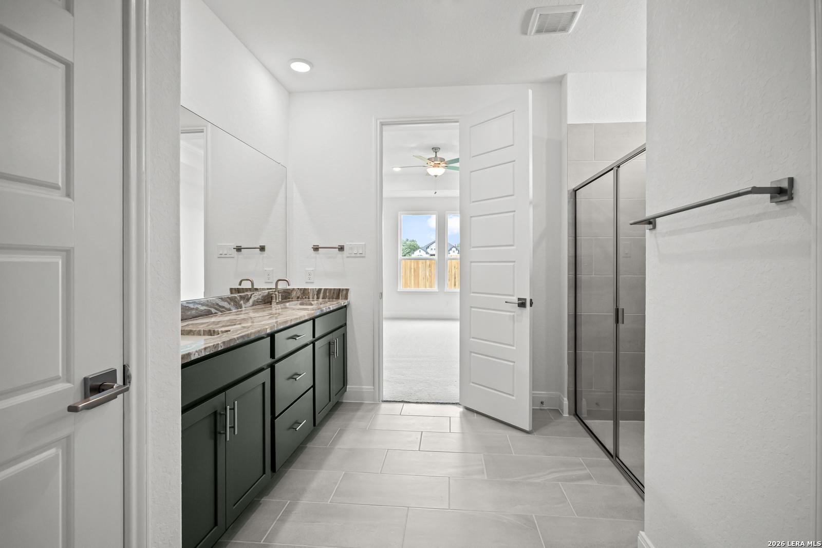 Modern primary bathroom with dual-sink vanity and glass-enclosed shower in The Lanier G home, The Reserve at Potranco Oaks