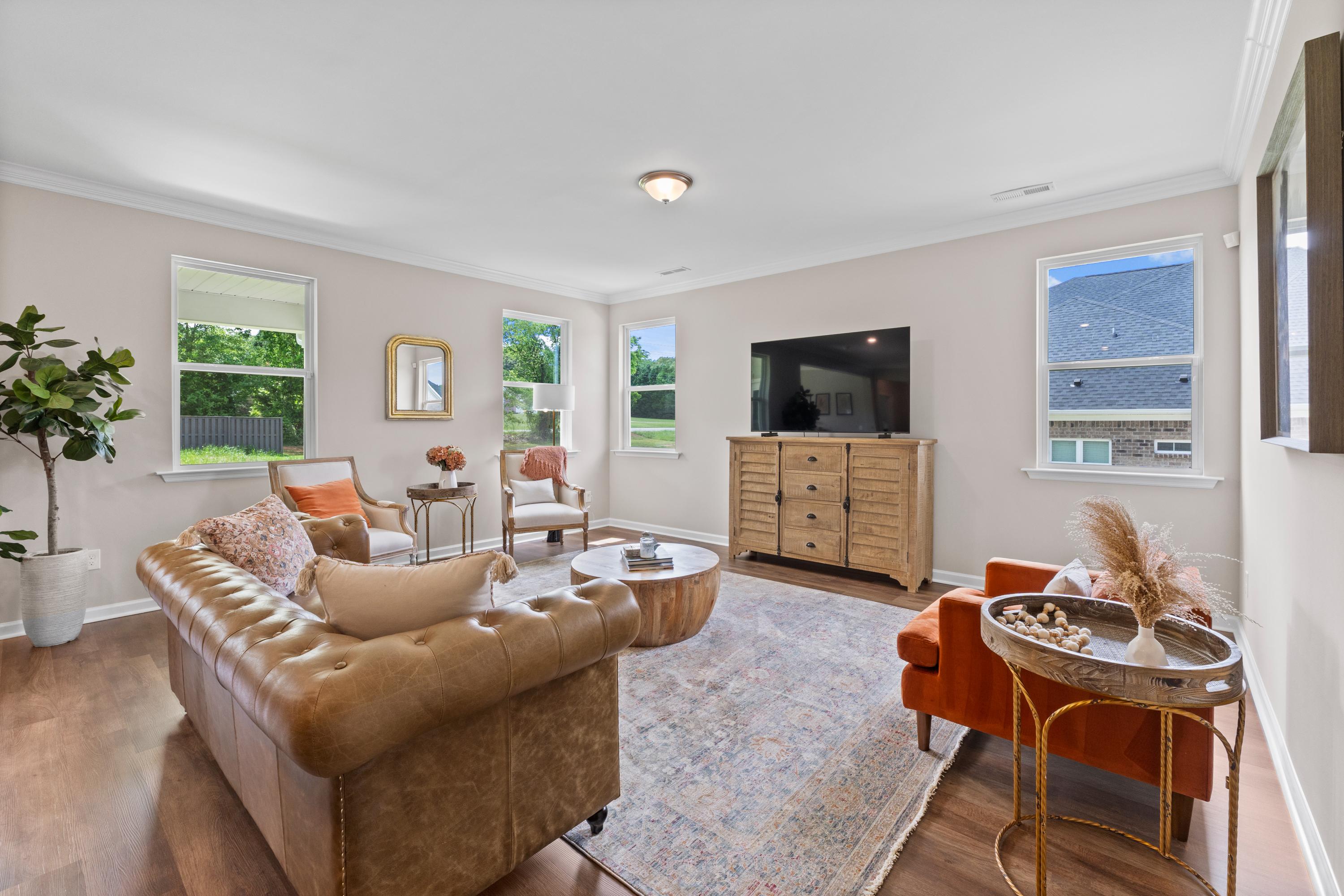 Spacious living room at Riverton Preserve in Huntsville Alabama with leather sofa, wooden accents, large windows, and neutral decor