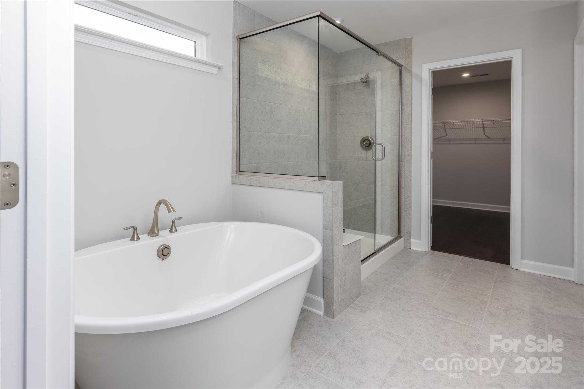 Elegant master bathroom with freestanding tub, glass shower, and walk-in closet in Davidson Homes The Chestnut F, Belmont, NC