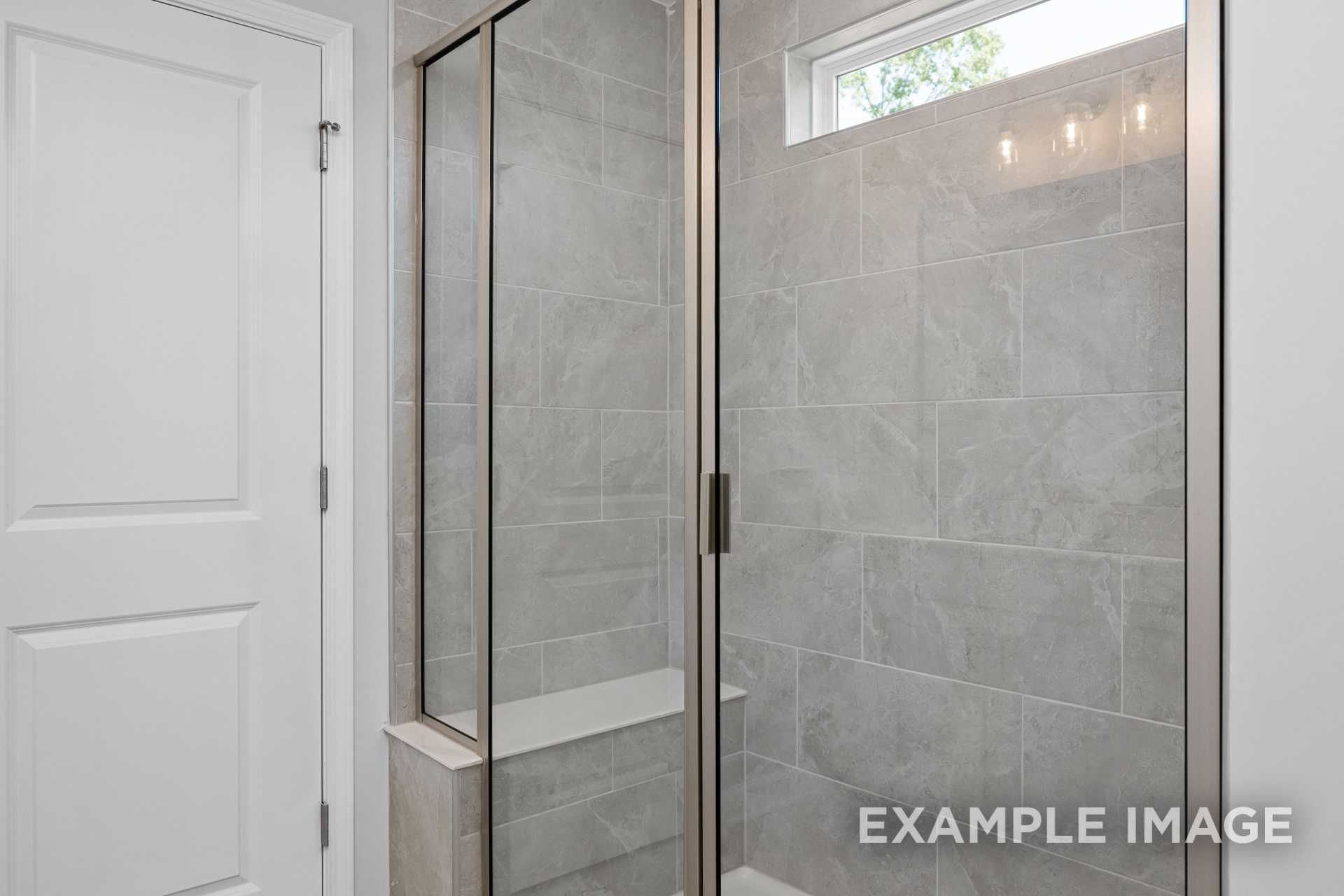 Modern master bathroom shower in The Preston B with gray subway tile, glass enclosure, and built-in bench