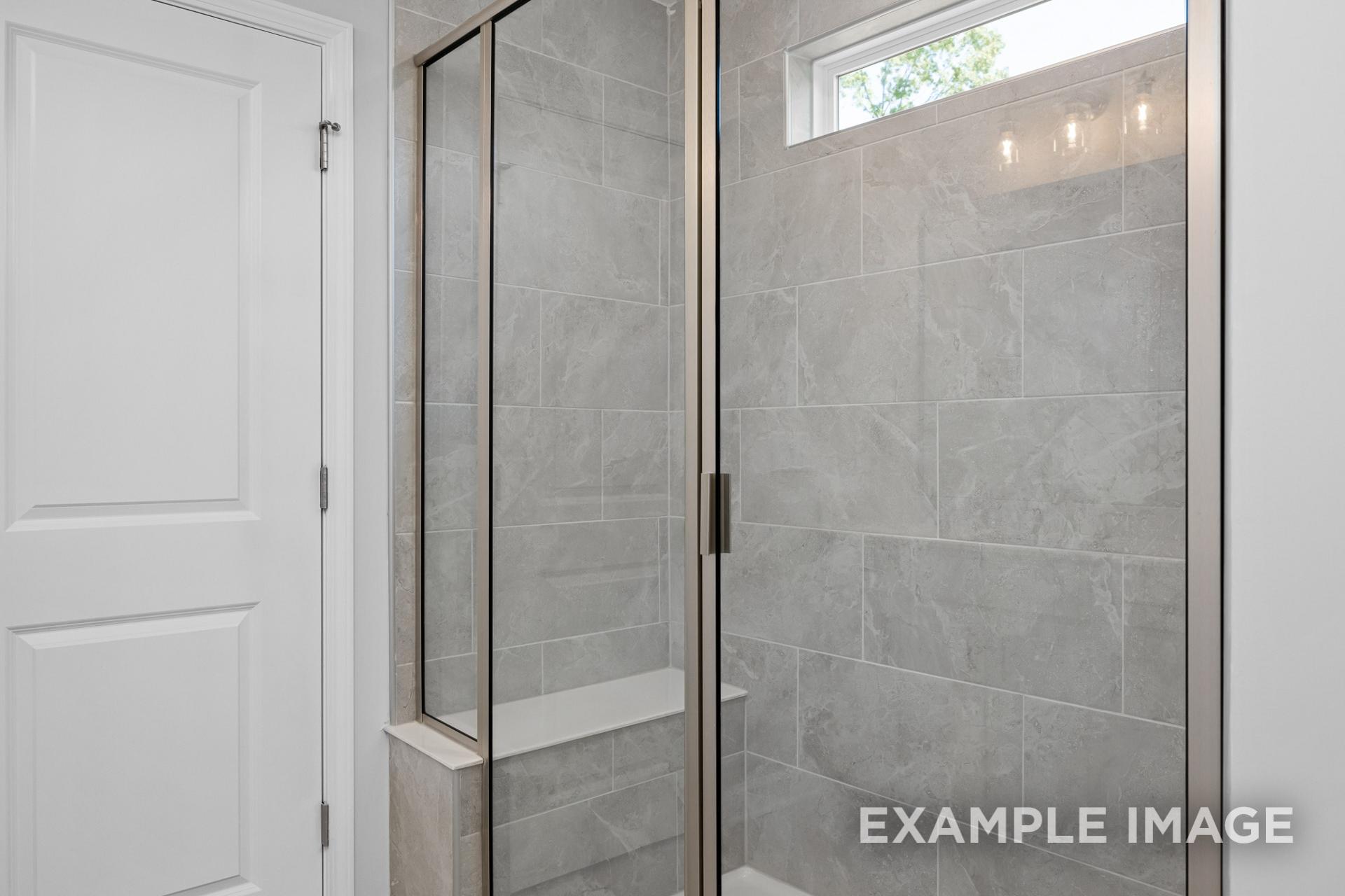 Modern master bathroom shower in The Preston B with gray subway tile, glass enclosure, and built-in bench