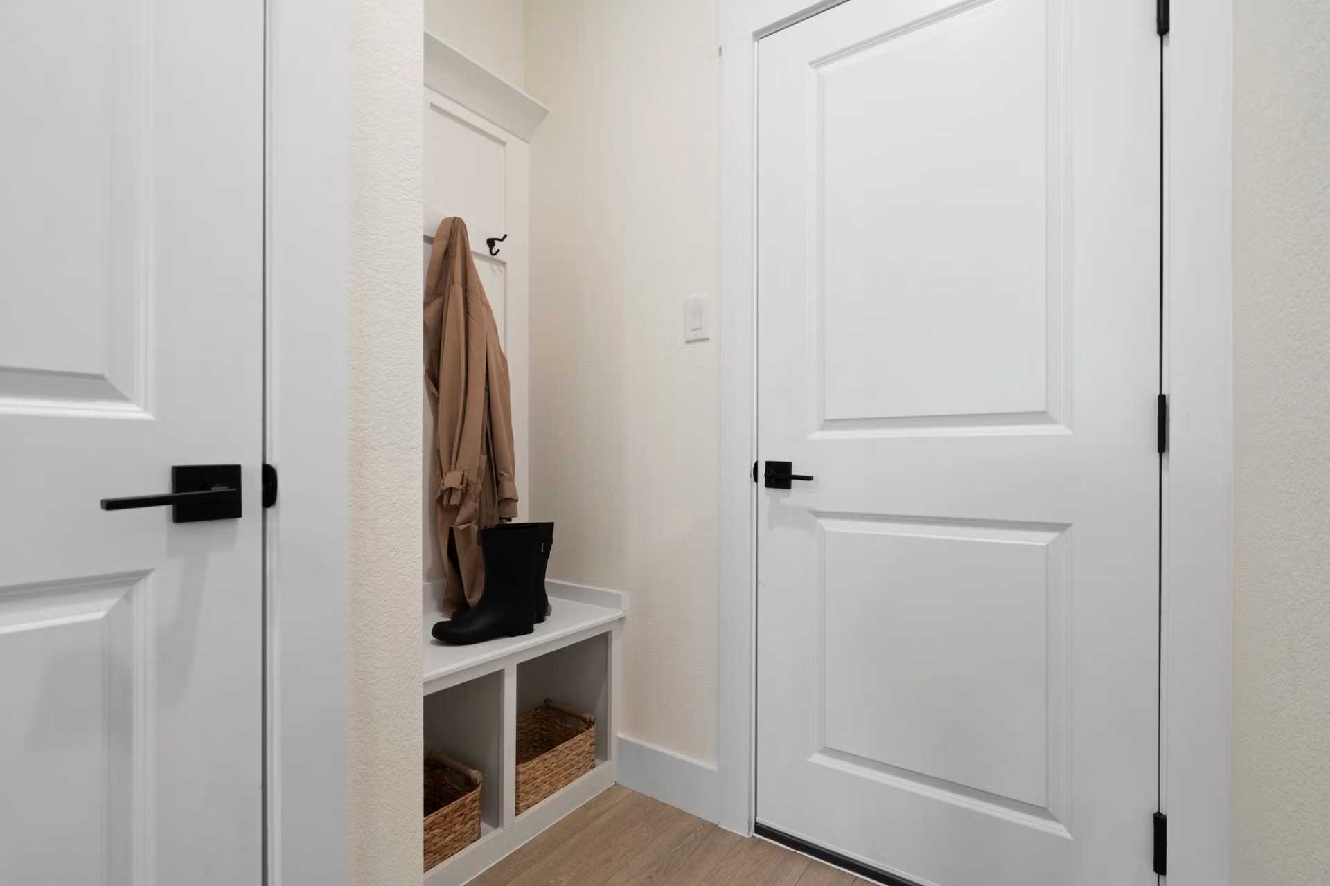 Functional mudroom entry with coat hooks, built-in bench, boots, and wicker storage in Davidson Homes The Wake D, Wylie, Texas