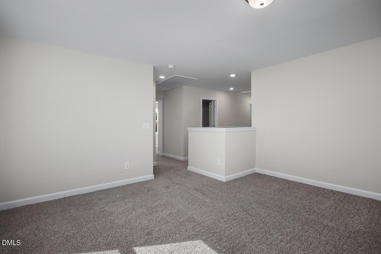 Upstairs hallway with beige walls, gray carpet flooring, and white railing in Davidson Homes The Grace C, Lillington, NC