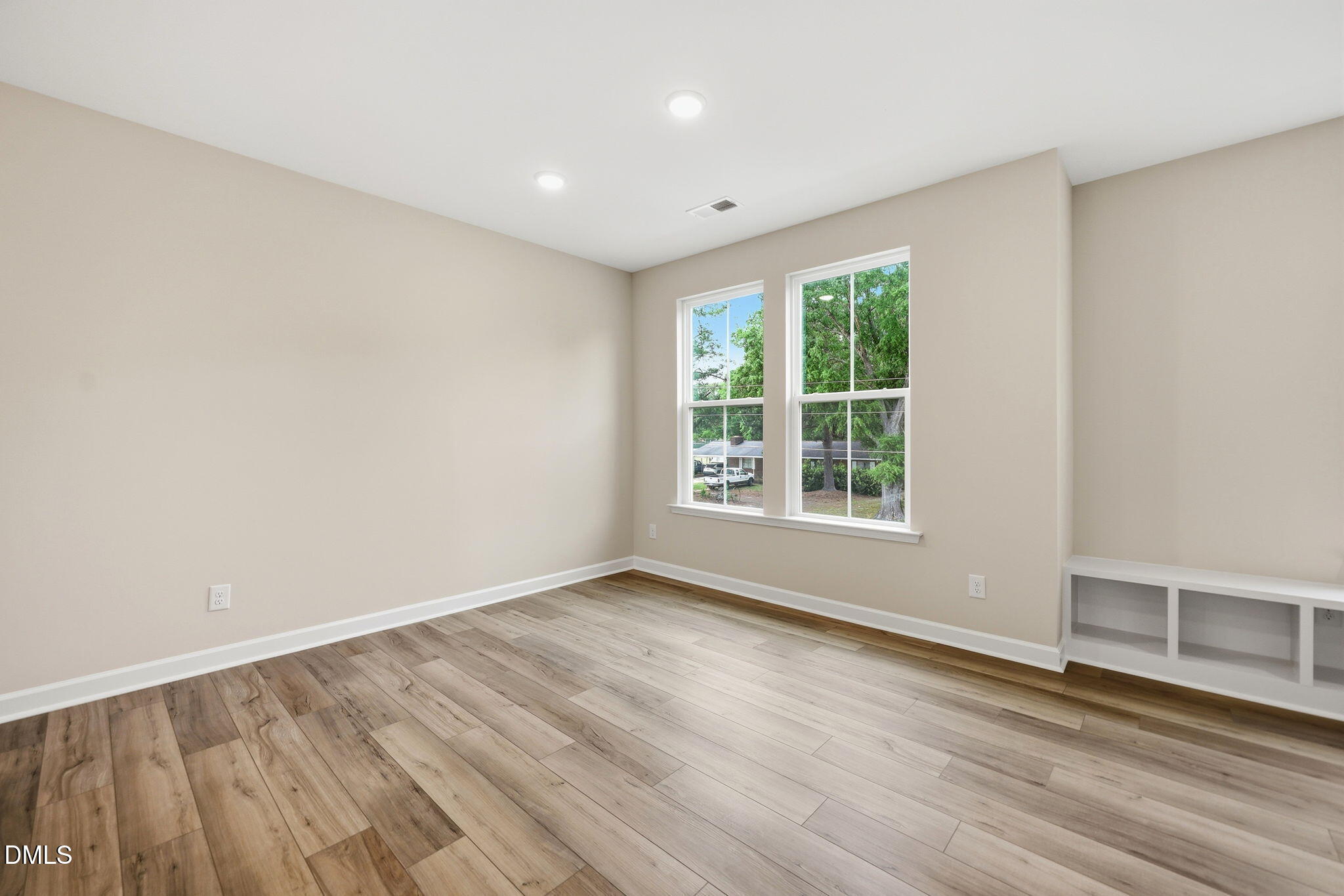 Bright, spacious bedroom with wood-style flooring and built-in shelving in The Mitchell floor plan at Camden Park.