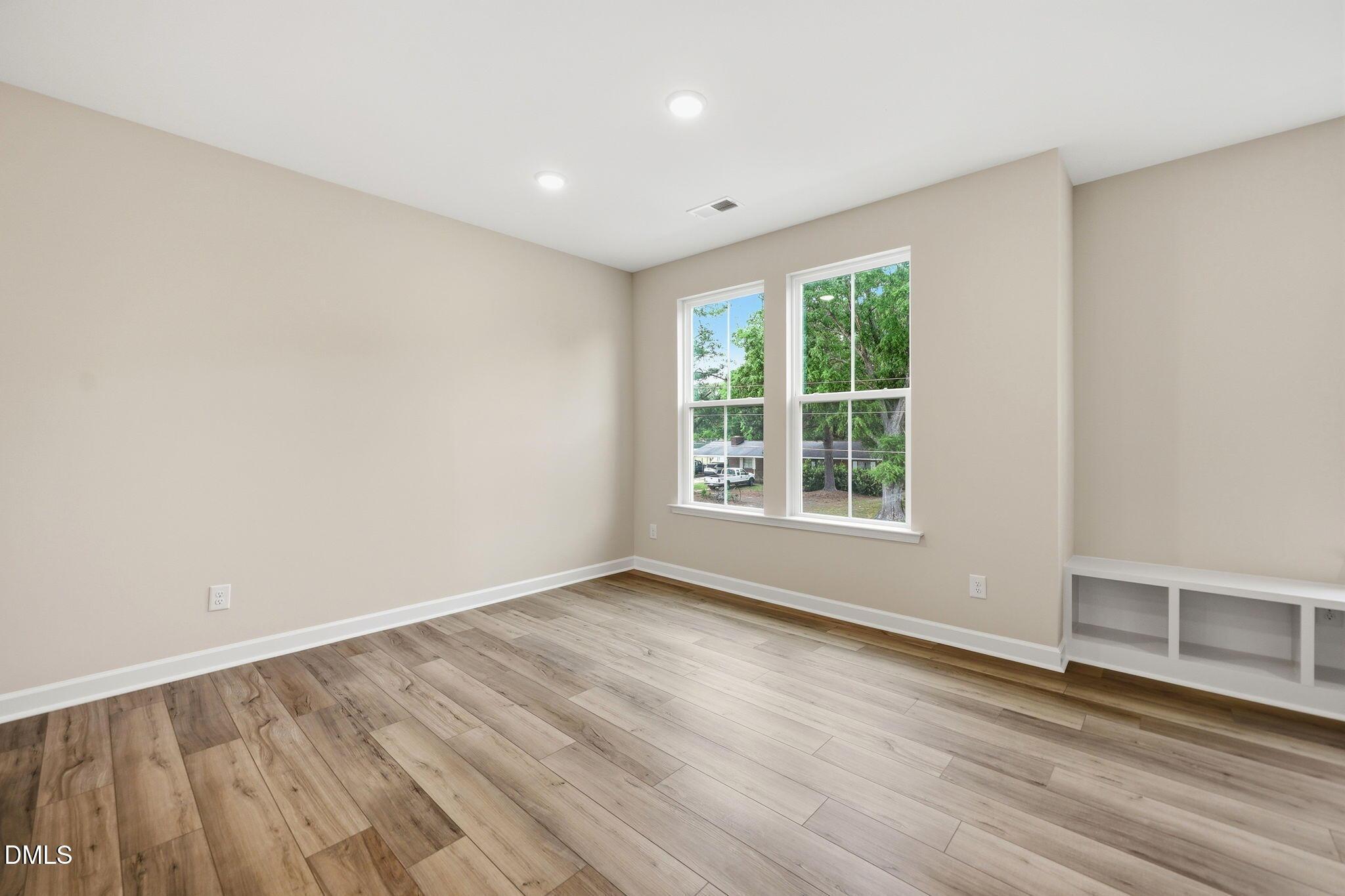 Bright, spacious bedroom with wood-style flooring and built-in shelving in The Mitchell floor plan at Camden Park.