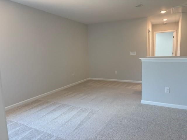 Spacious upstairs loft with gray walls, neutral carpet, and white railing in Davidson Homes The Rabun A, Winder, Georgia