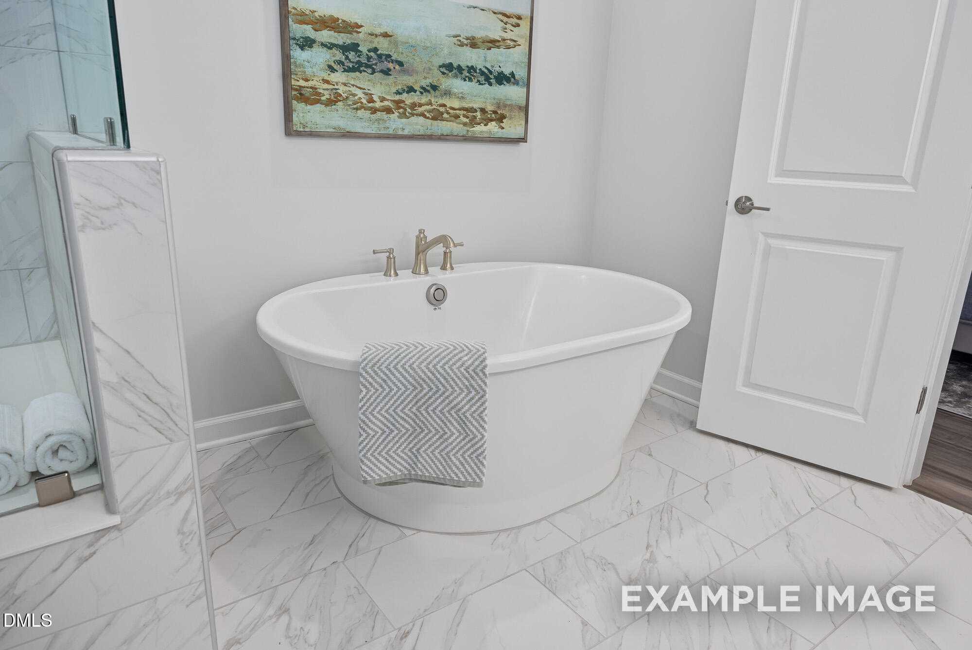 Luxurious master bathroom featuring freestanding soaking tub, marble tiles, and abstract wall art in Davidson Homes The Cypress B II, Angier, NC