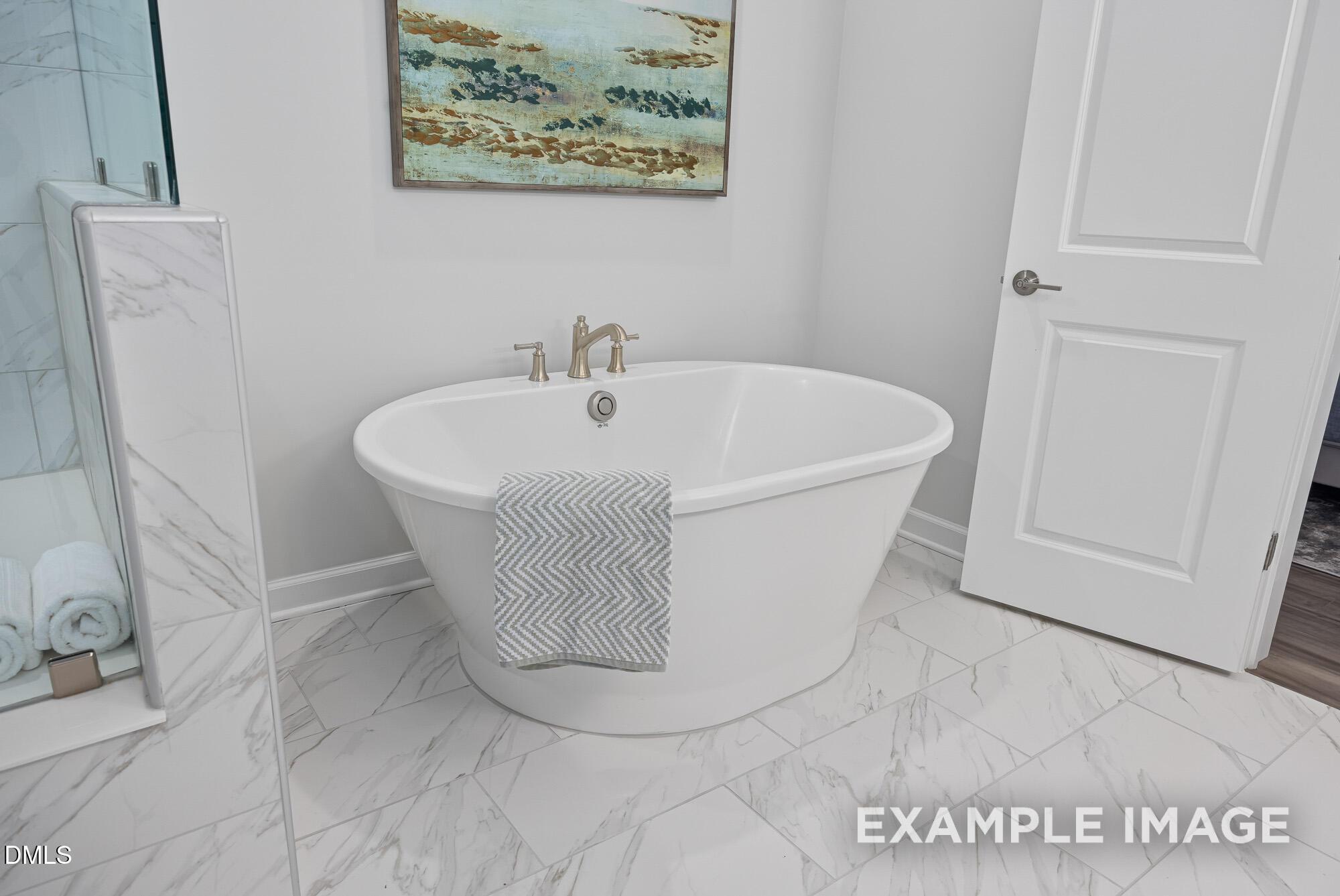 Freestanding soaking tub in luxurious marble master bathroom with glass shower in Davidson Homes The Cypress B II, Angier, NC