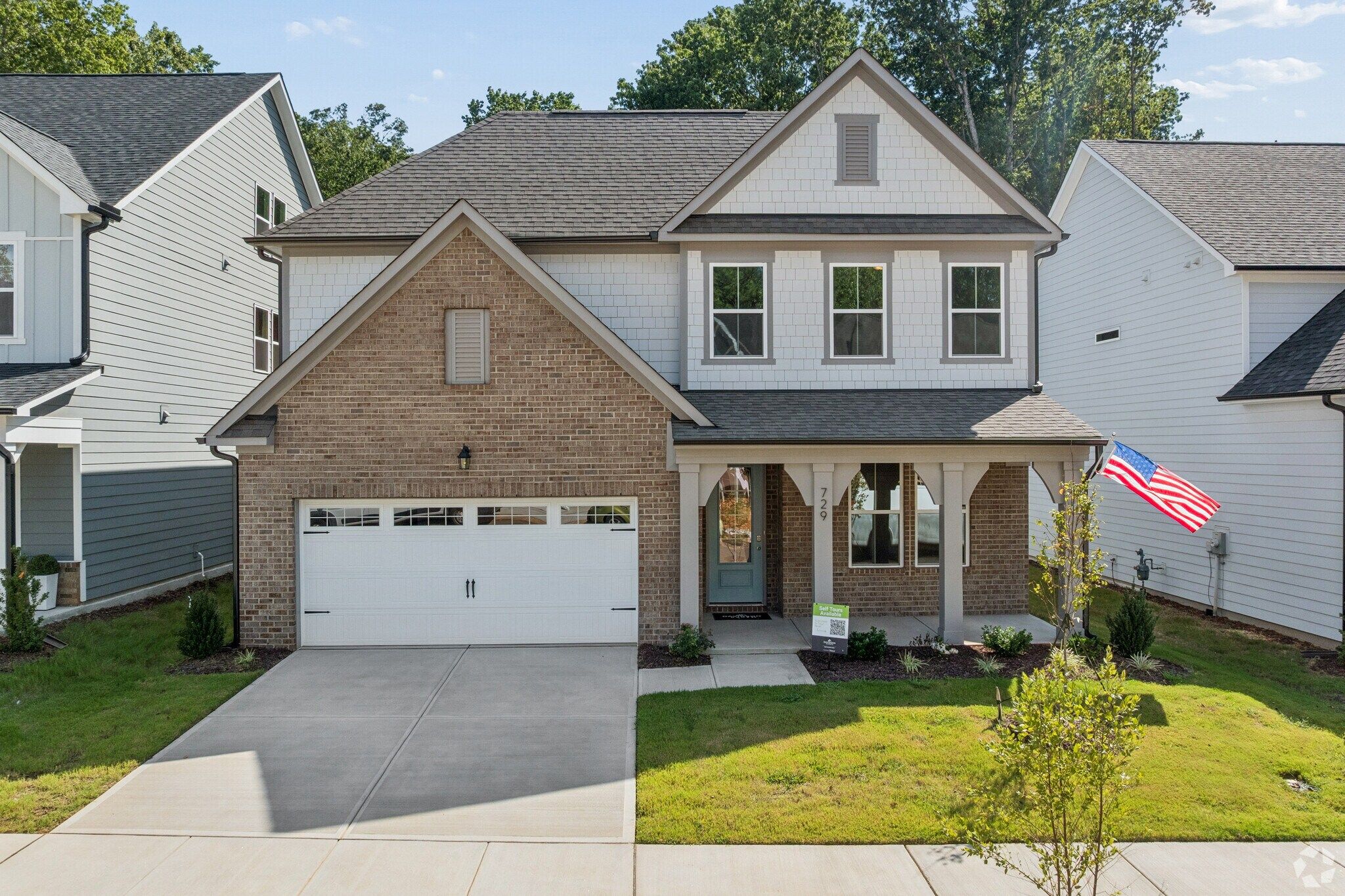 Two-story brick new construction home at Sage on North Main in Wake Forest, NC by Davidson Homes with covered porch and garage
