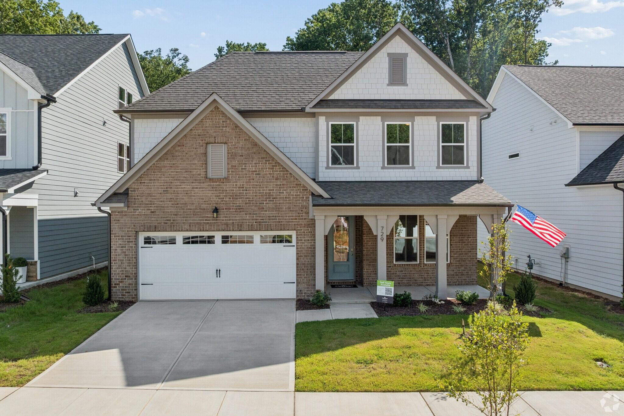 Two-story brick new construction home at Sage on North Main in Wake Forest, NC by Davidson Homes with covered porch and garage