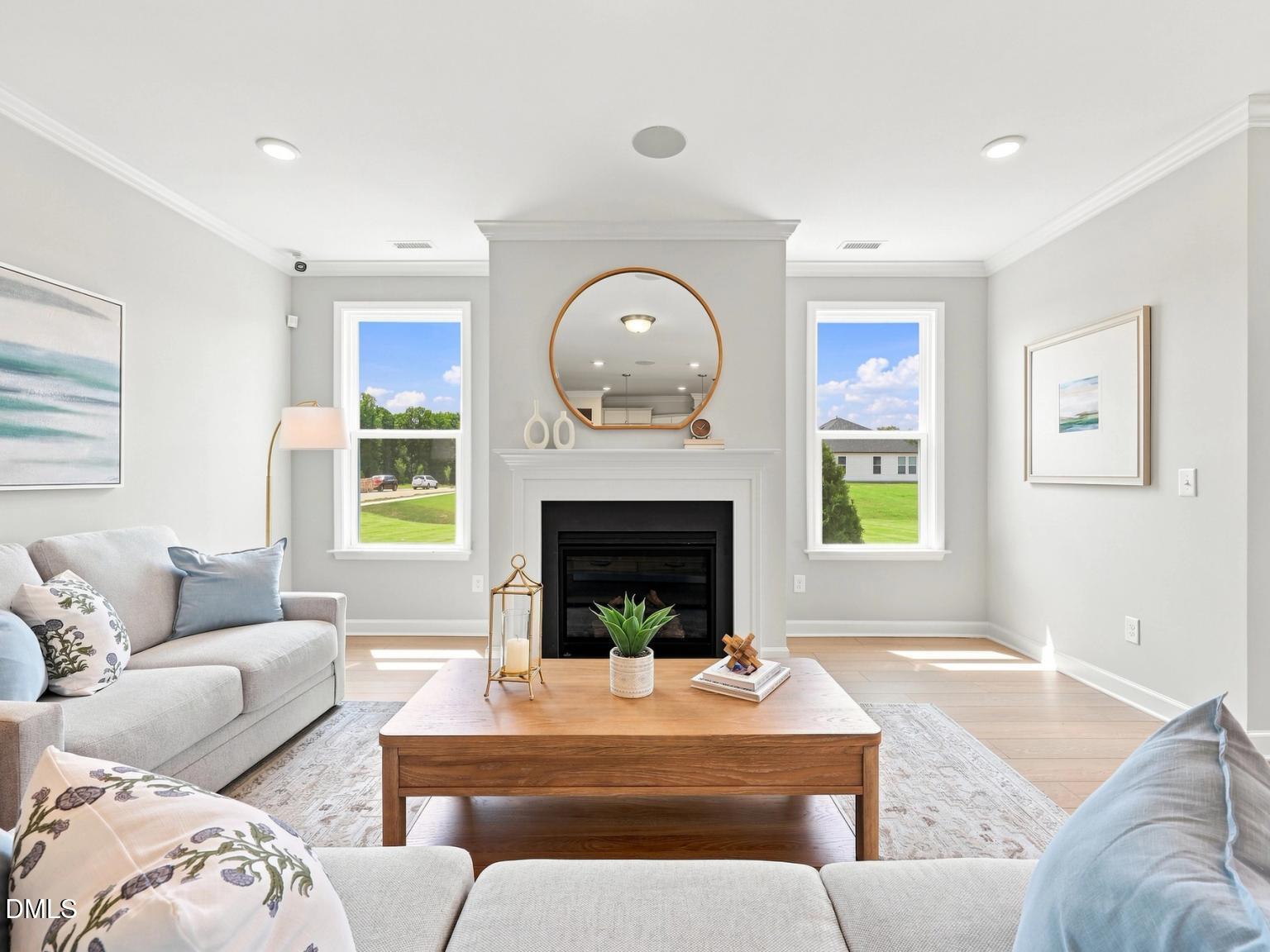 Bright living room with fireplace and round mirror in The Daphne C floor plan at Woodland Crossing, Zebulon, North Carolina.