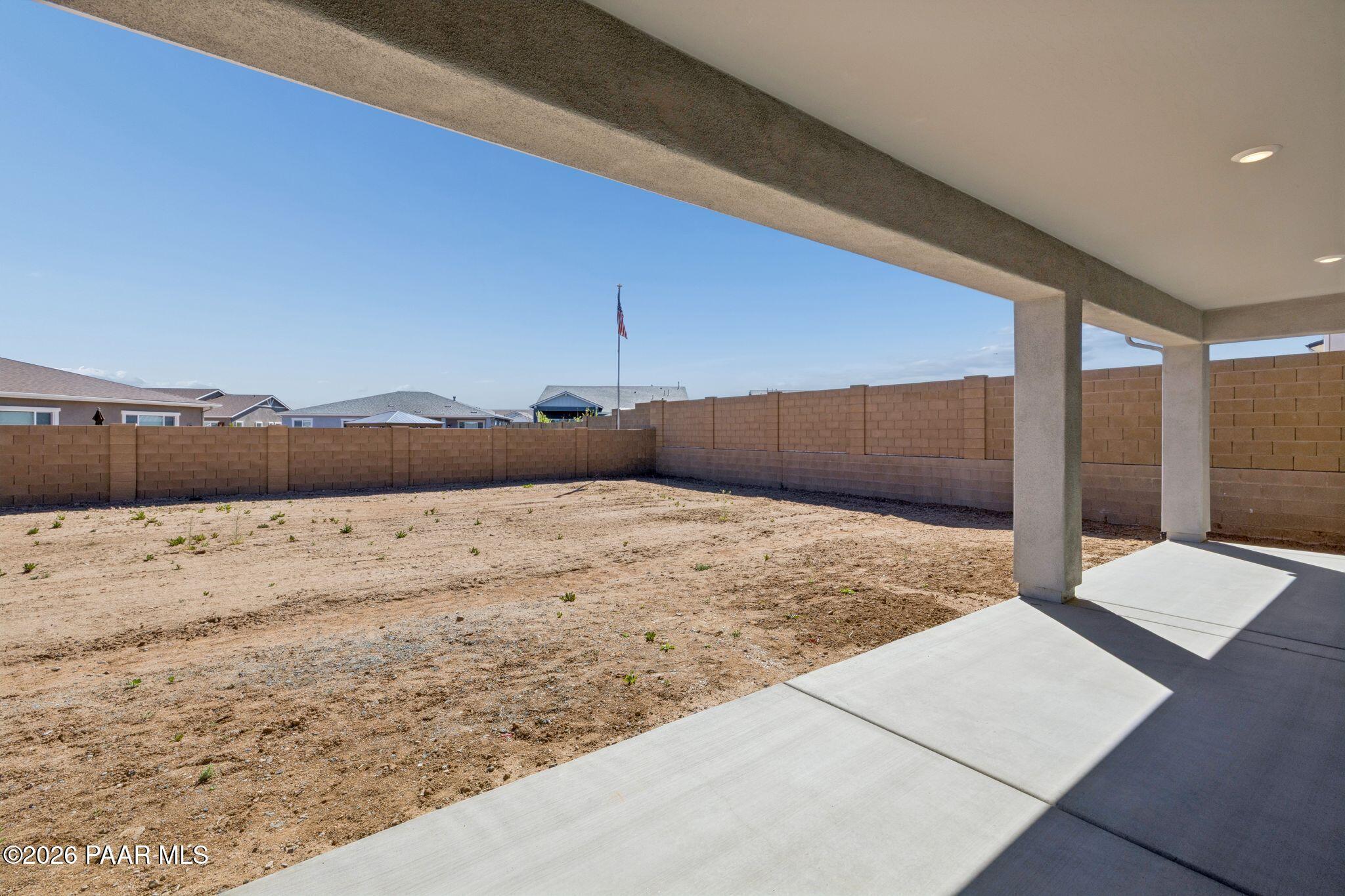Covered back patio with expansive dirt yard, block fence, and desert view in Davidson Homes The Monarch A, Prescott, AZ