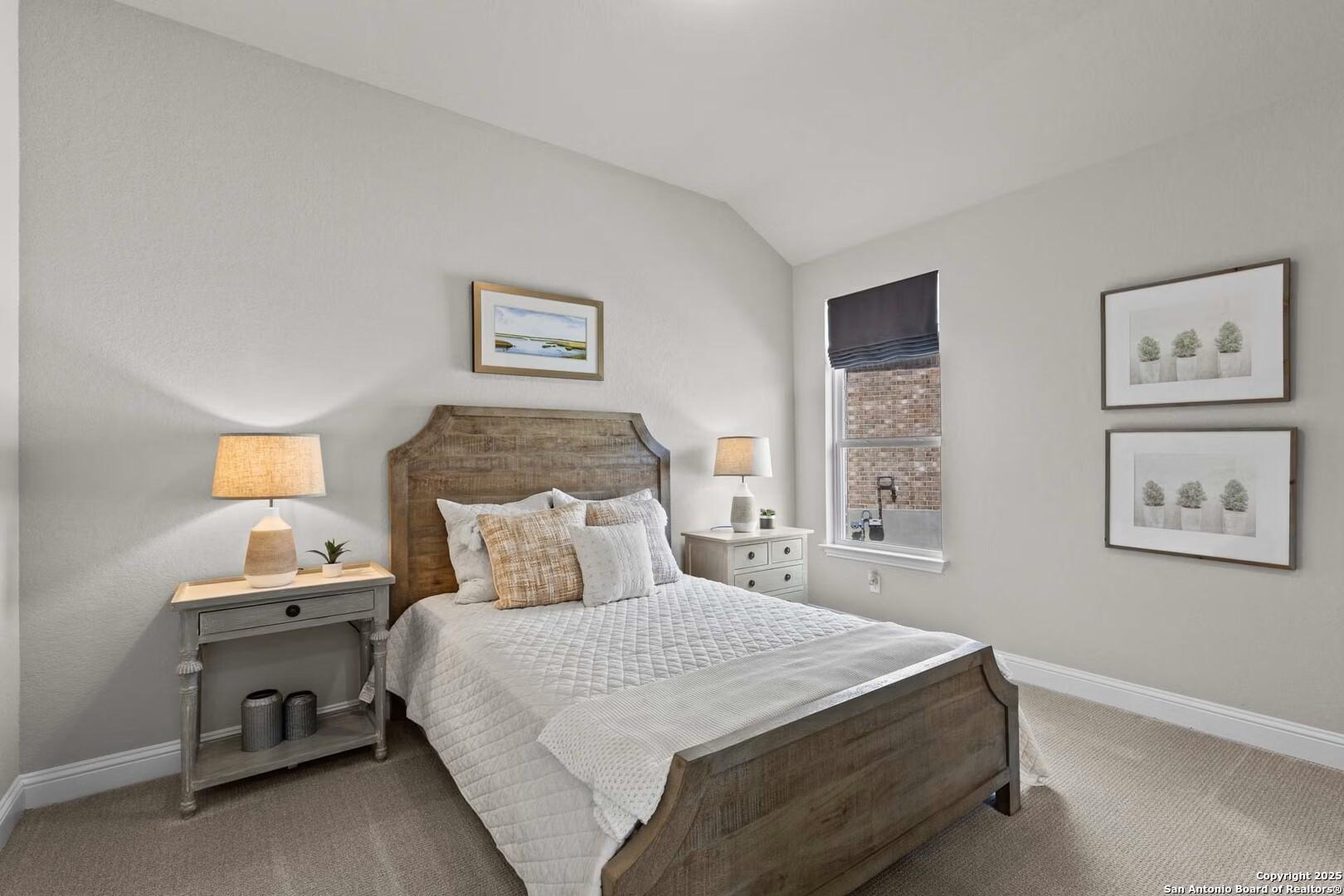 Cozy guest bedroom with wooden bed, white bedding, nightstands, and succulent wall art in Davidson Homes The Garner B, Castroville, Texas