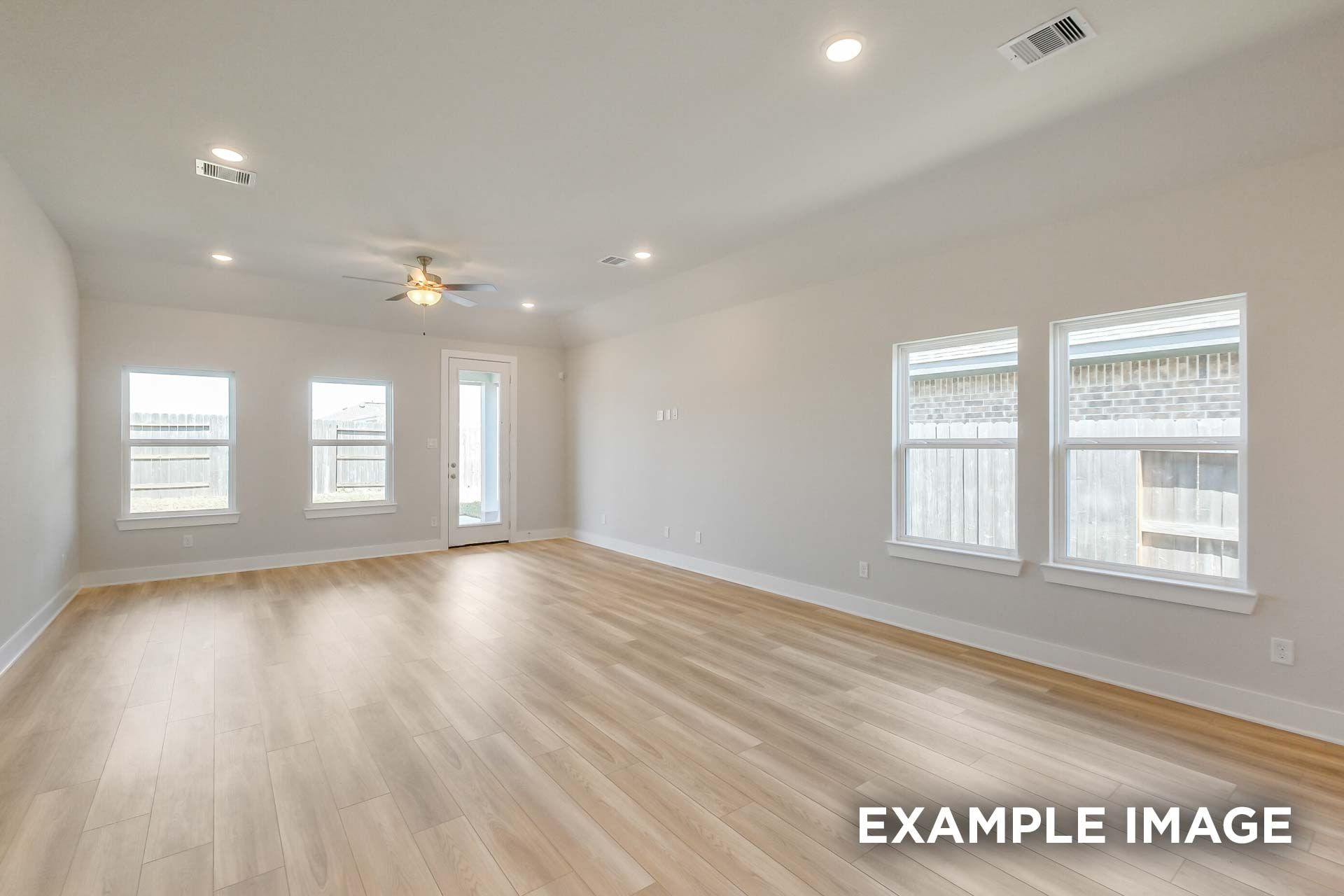 Spacious open-concept living room in The Luna K with light hardwood floors, neutral walls, large windows, and ceiling fan