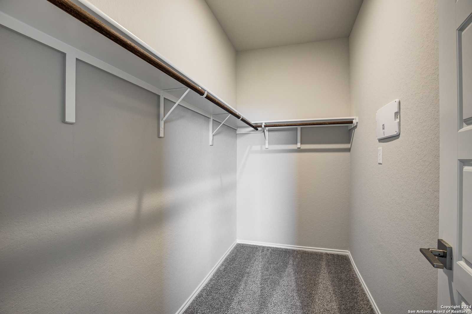 Spacious walk-in closet with built-in shelving and hanging rods in master suite, Davidson Homes The Frio B, San Antonio, Texas