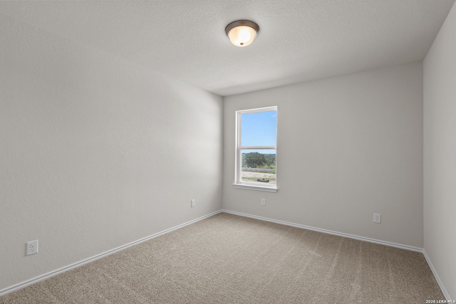 Bright, carpeted bedroom with neutral walls in The Gillian B floor plan at Meadows at Oak Creek, San Antonio, Texas.