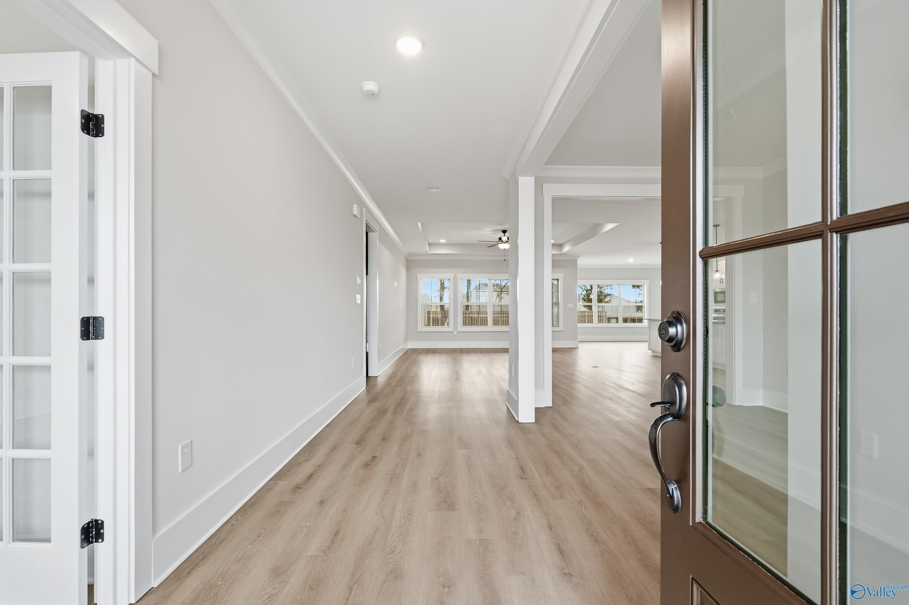Bright entry hallway with light oak floors, French doors, and glass front door view of pool in Davidson Homes The Finleigh, Meridianville, Alabama