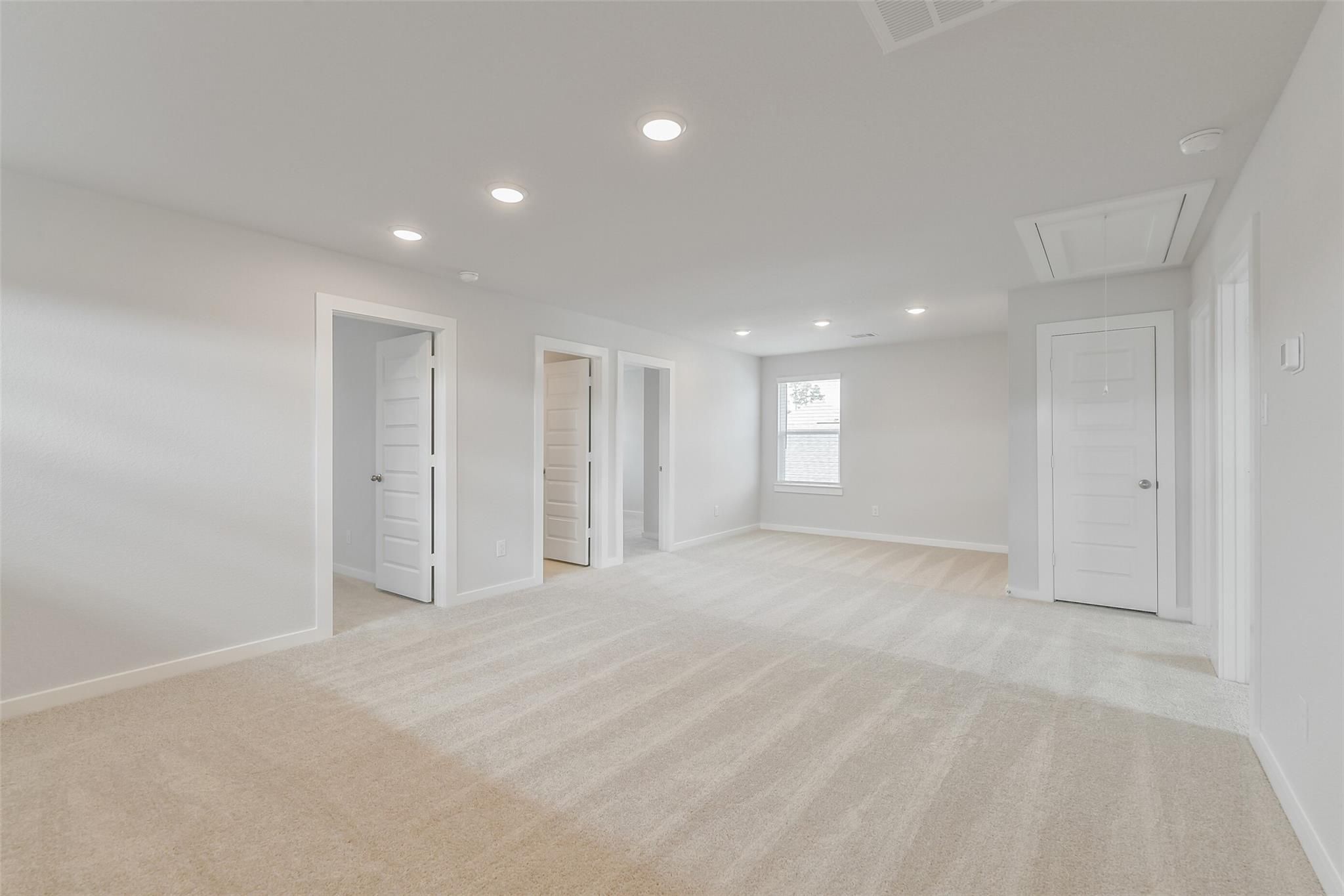 Spacious upstairs hallway with bedroom doors, large window, and recessed lighting in 5-bedroom Davidson Homes The Brazos E, Cleveland, Texas